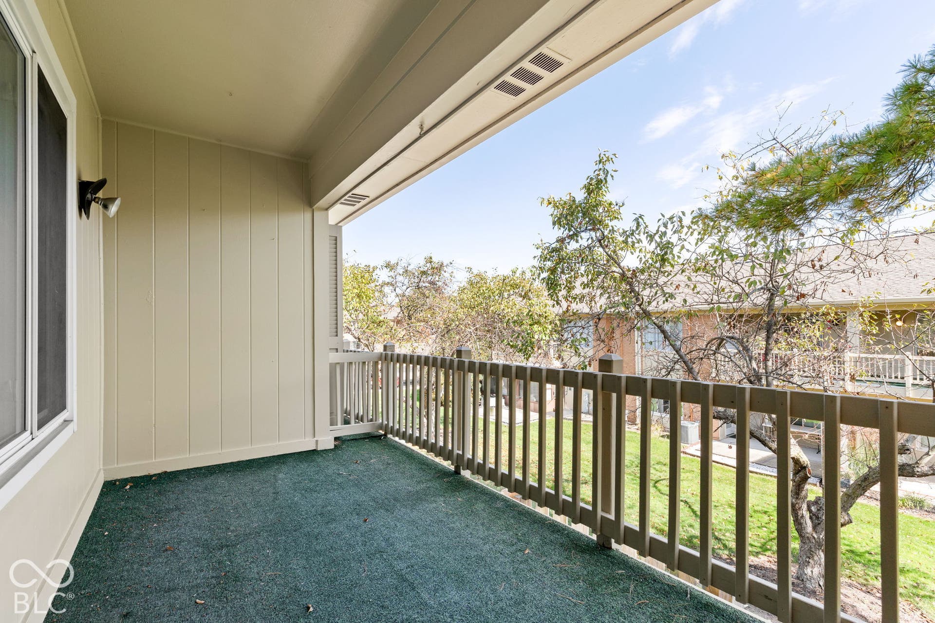 Covered balcony featuring vertical siding, a protective rail, and an attached wall-mounted light fixture