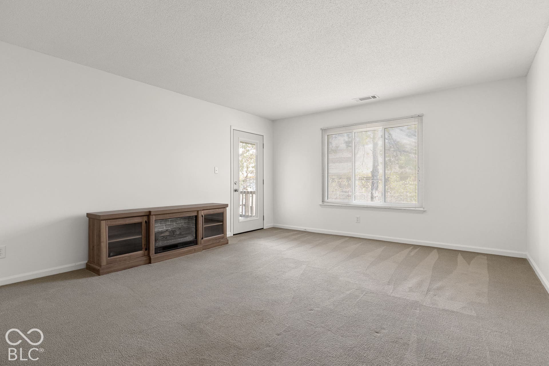 Neutral interior featuring wall-to-wall carpeting, a multi-pane window, and a glass-paneled exterior door