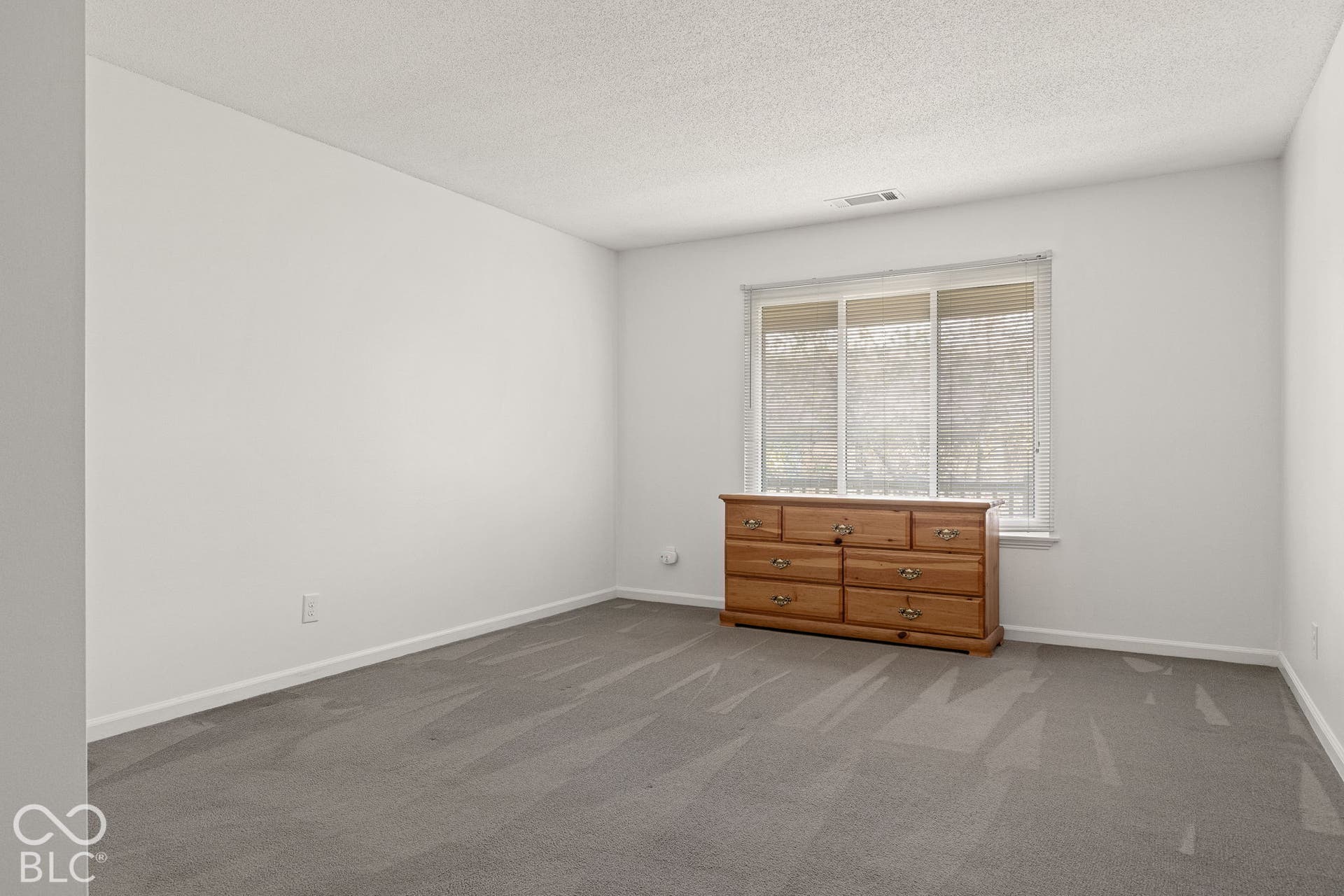 Neutral interior room featuring neutral carpeting, white walls, and a multi-pane sliding window