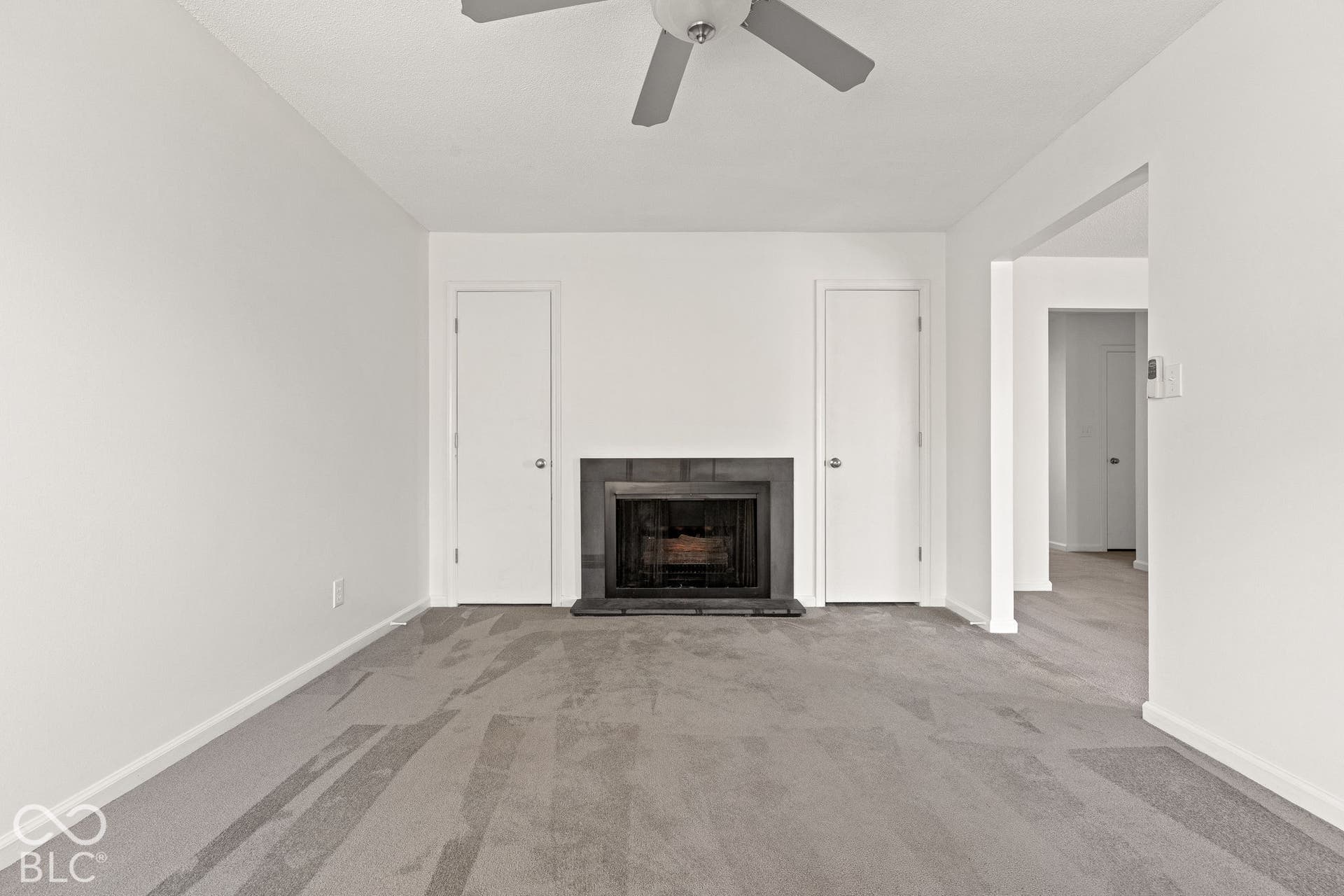 Fireplace with a dark tile surround and hearth, carpeted flooring, and a ceiling fan