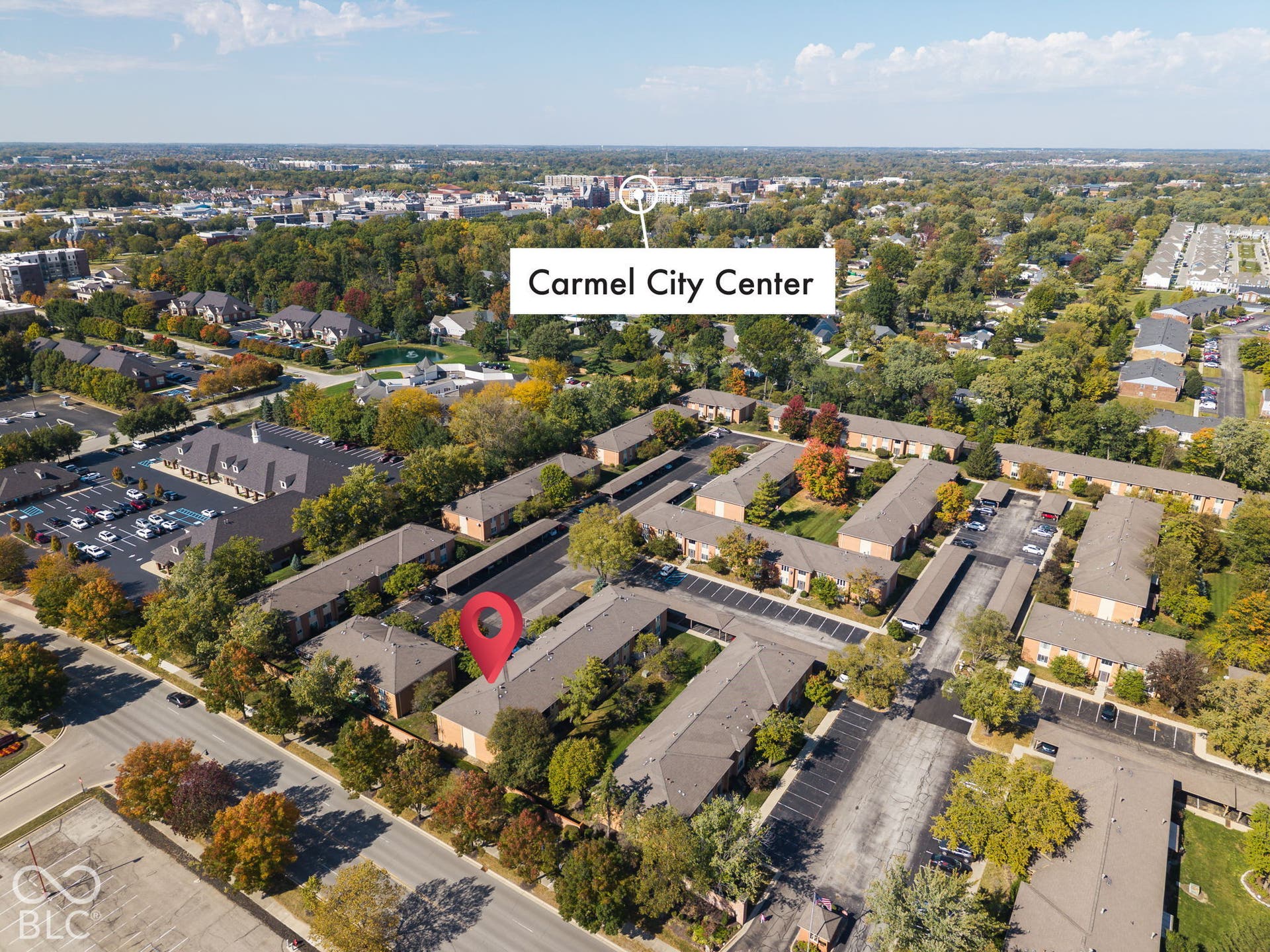 Aerial perspective of a multi-unit property featuring dedicated surface parking, paved driveways, and mature landscaping