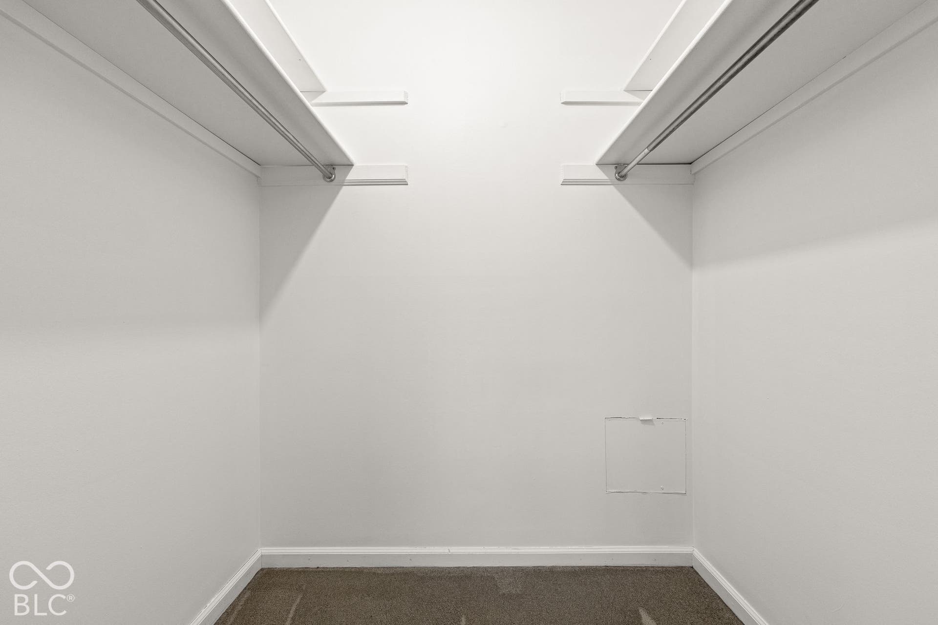Storage closet featuring dual tiers of built-in shelving and integrated hanging rods