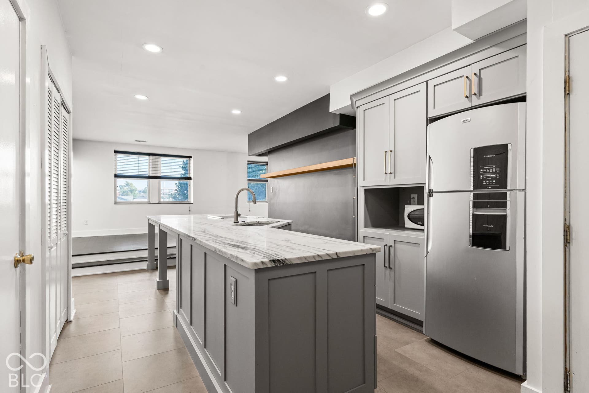 Kitchen featuring a central island with stone-finish countertops, stainless steel appliances, custom grey cabinetry, recessed ceiling lighting, and tile flooring