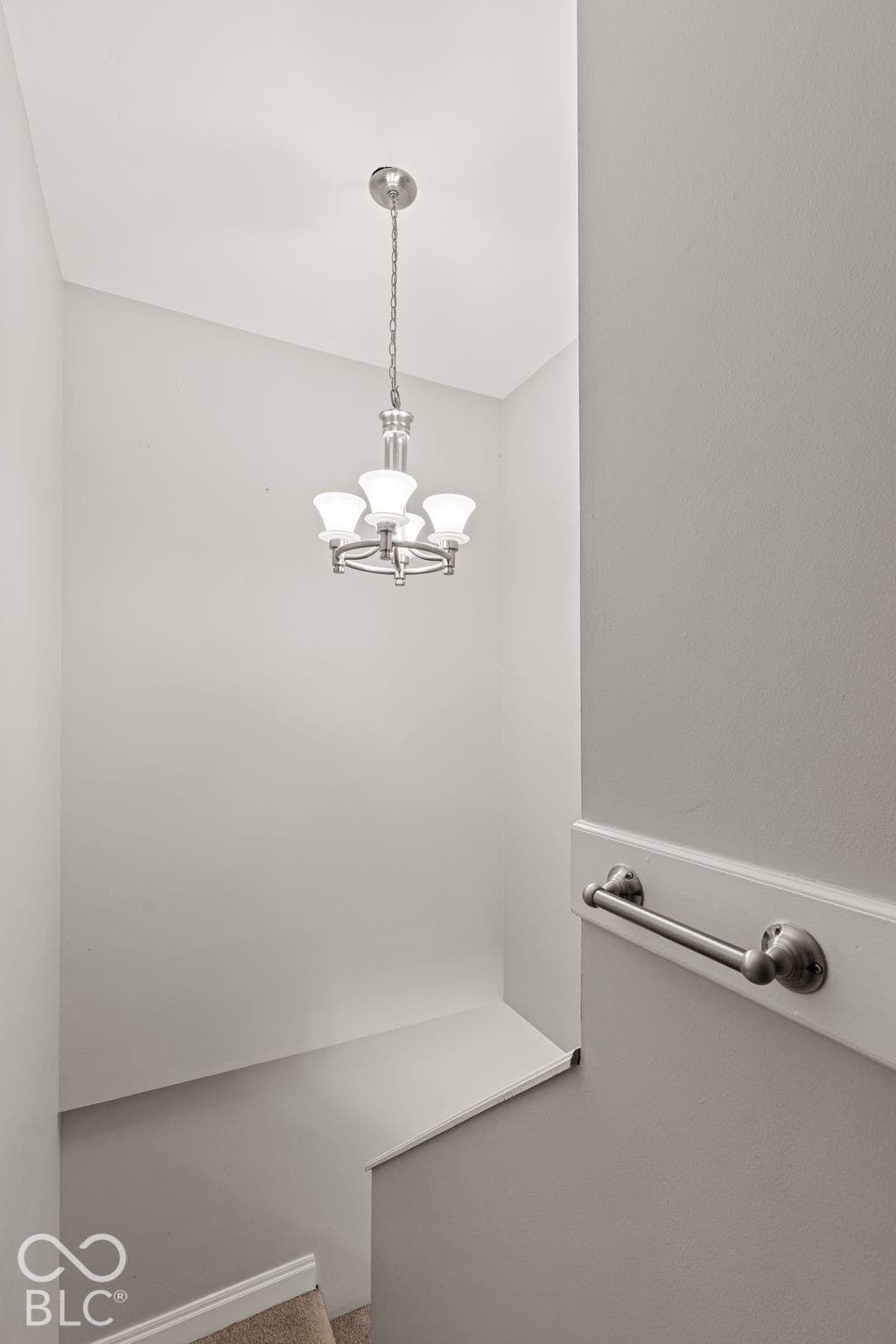 Polished nickel chandelier with four frosted glass shades and mounted handrail with metallic finish