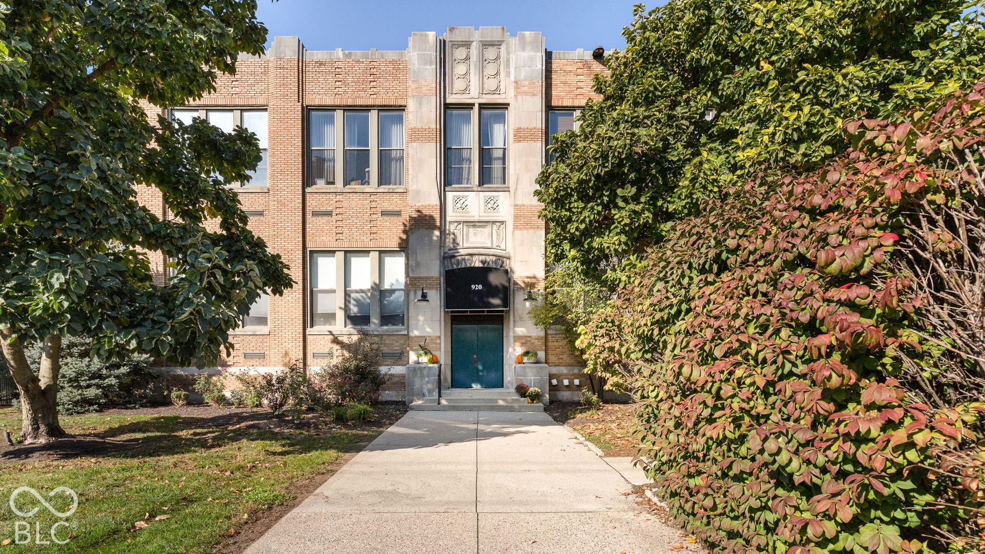 Brick facade featuring decorative stone accents, symmetrical multi-pane windows, and a covered entryway