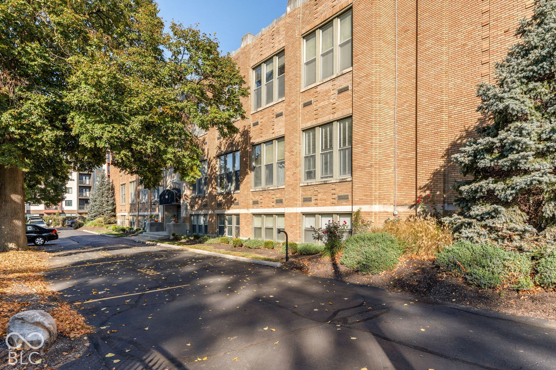 Multi-story brick exterior featuring large multi-pane windows, a recessed entryway with a rounded awning, and paved surface parking
