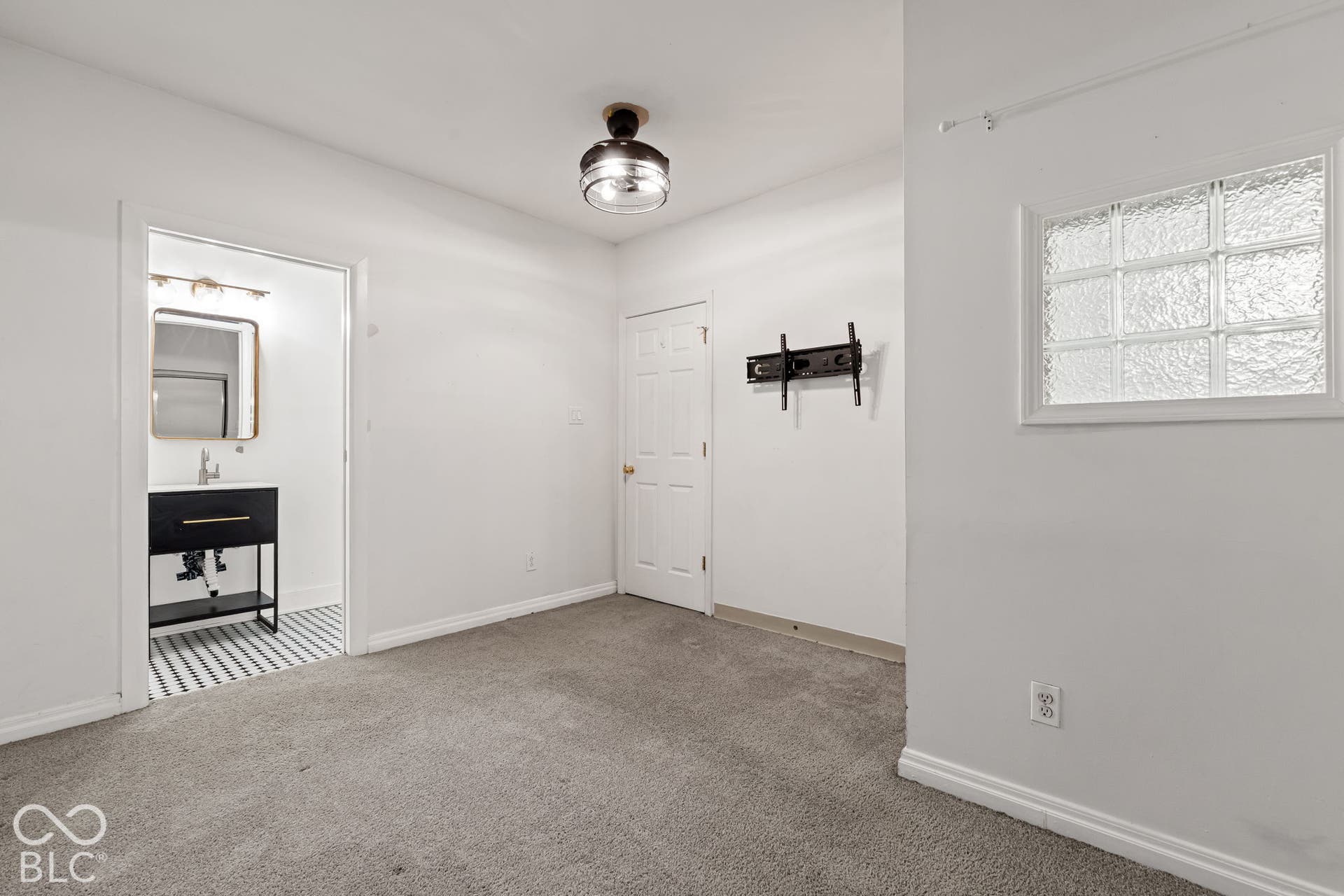 Interior space featuring neutral carpeting, a semi-flush mount ceiling light, and an inset glass block window