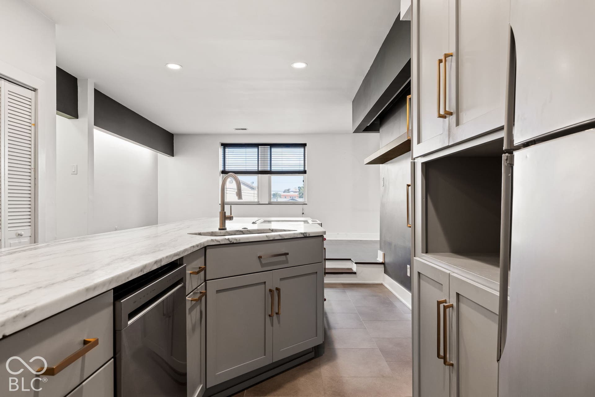 Kitchen featuring stone-patterned countertops, gray shaker-style cabinetry with gold-tone pulls, stainless steel dishwasher, recessed ceiling lighting, and tile flooring