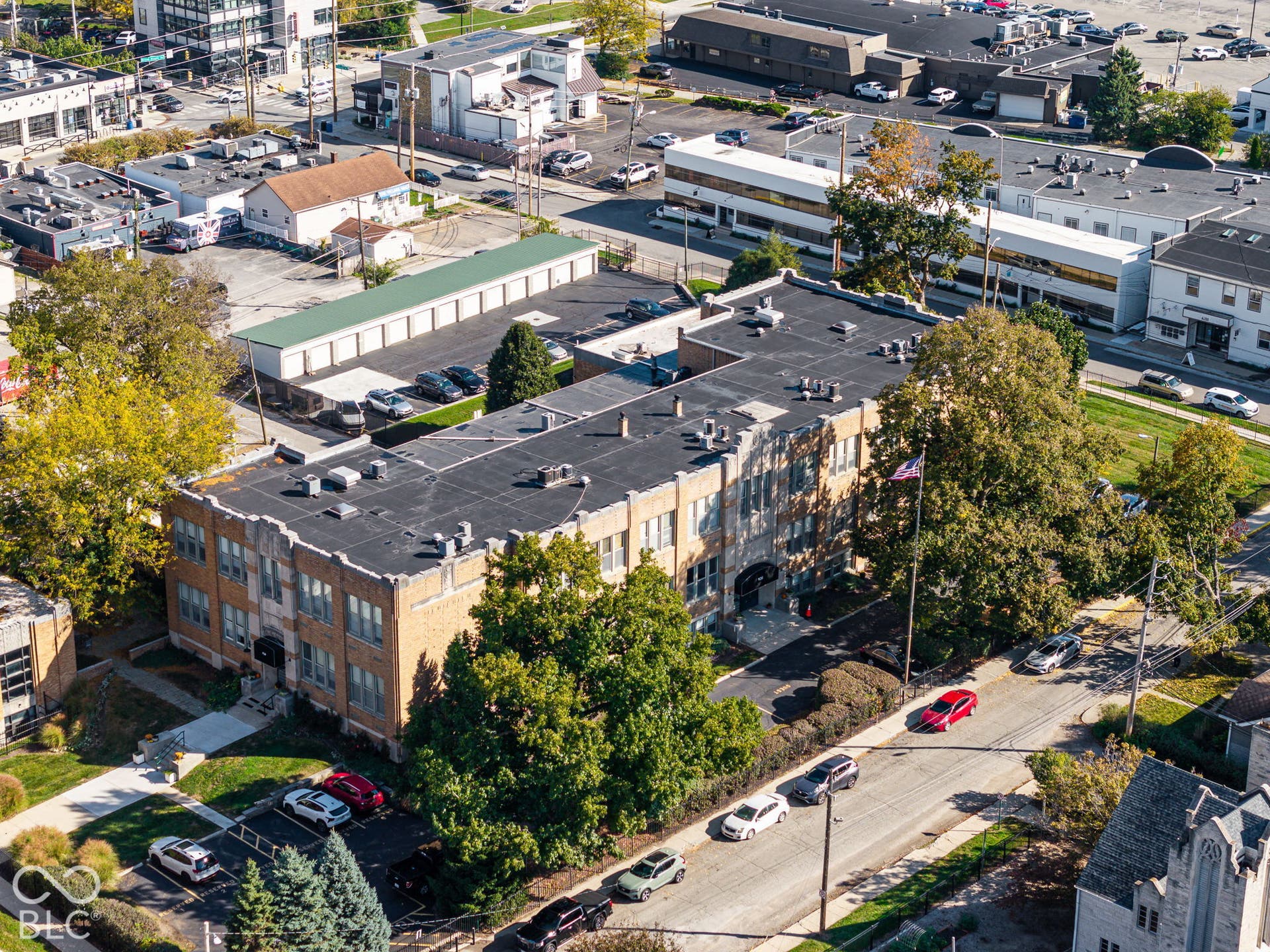 Multi-story masonry building featuring a flat roofline, extensive window grid, concrete foundation, and dedicated asphalt parking lot