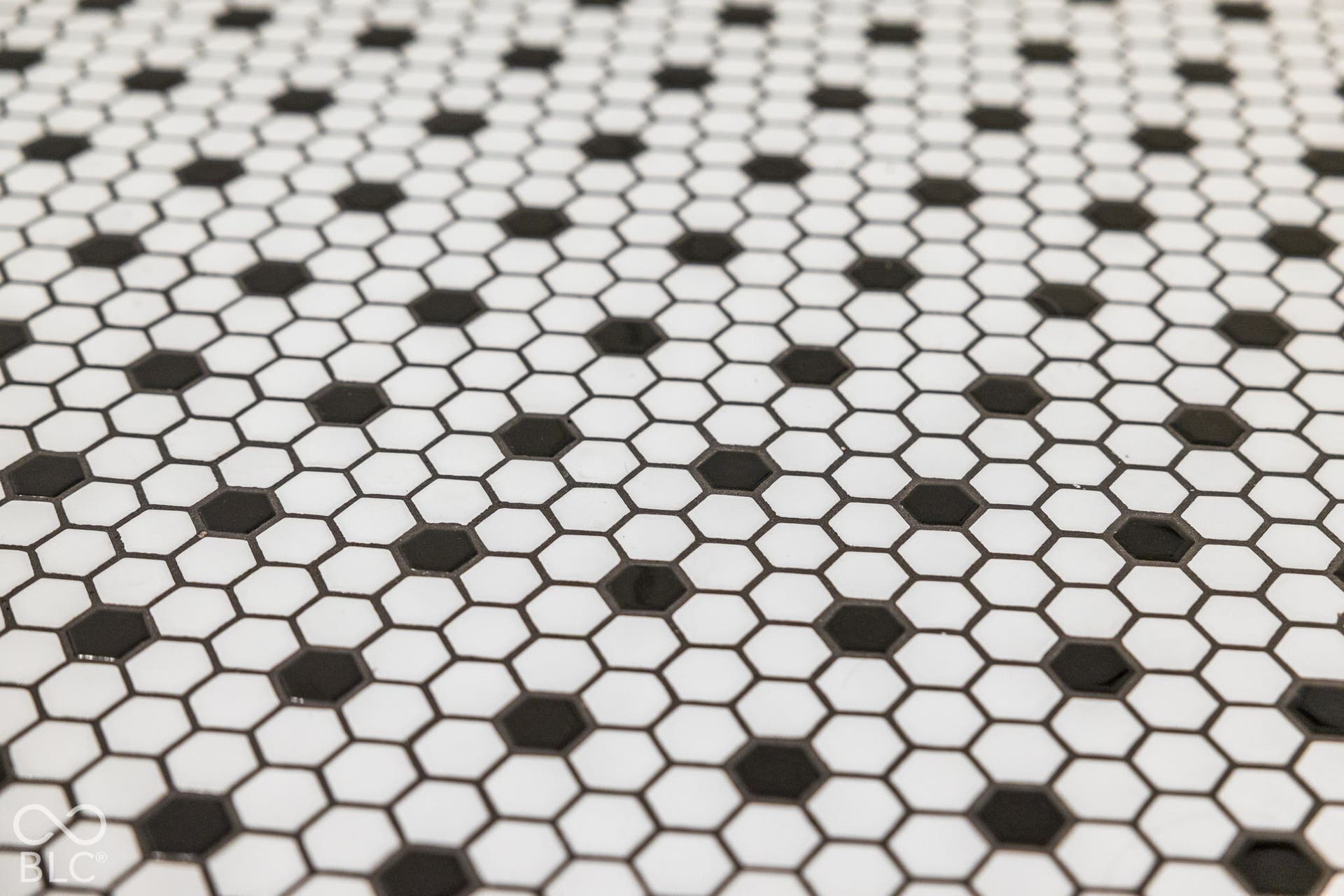 Matte-finish ceramic hexagonal tile featuring a high-contrast black and white geometric pattern