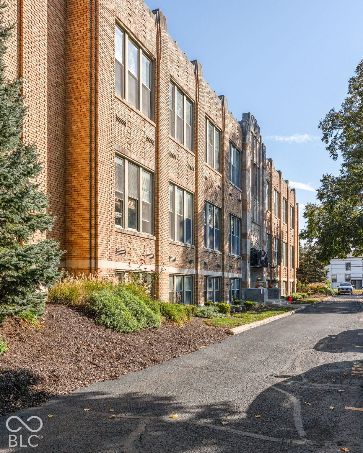 Multi-story brick exterior featuring recessed windows, stone detailing, vertical brick masonry accents, and manicured foundation landscaping