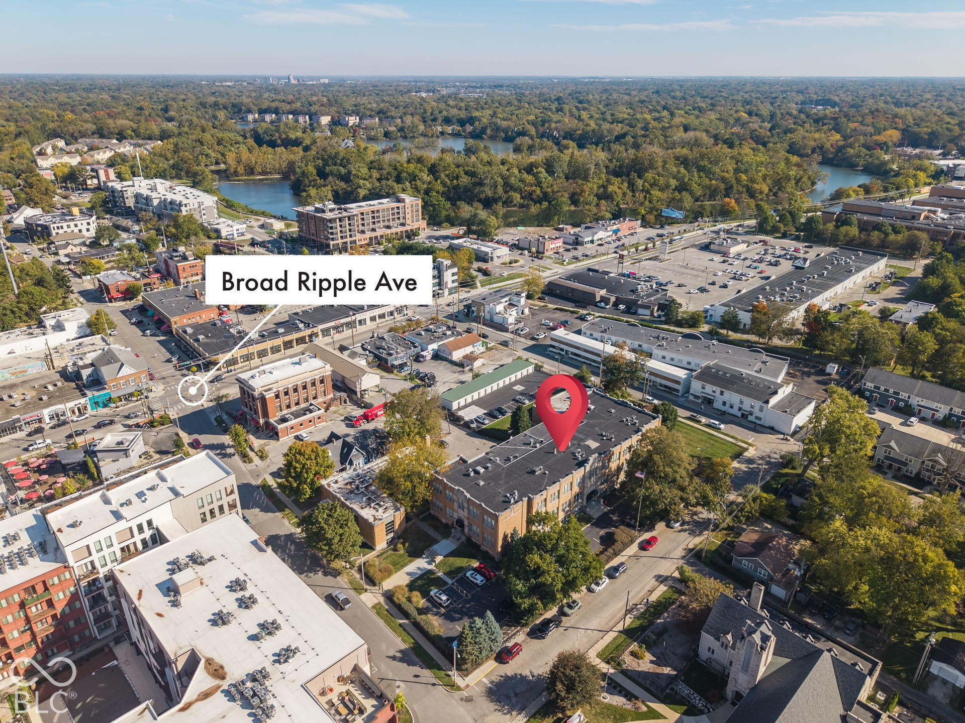 Aerial perspective of brick-exterior multi-story property featuring a flat roof and dedicated surface parking