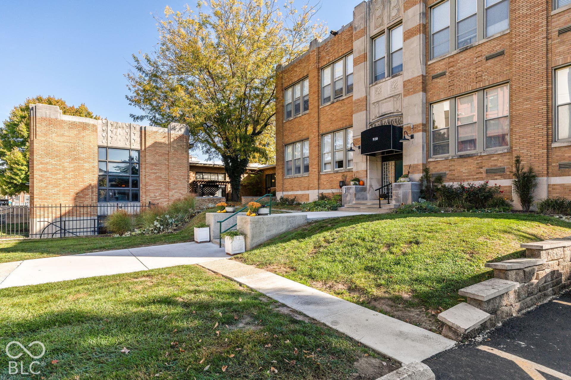 Exterior facade featuring multi-tone brick masonry, decorative stone detailing, large multi-pane windows, and a black metal awning
