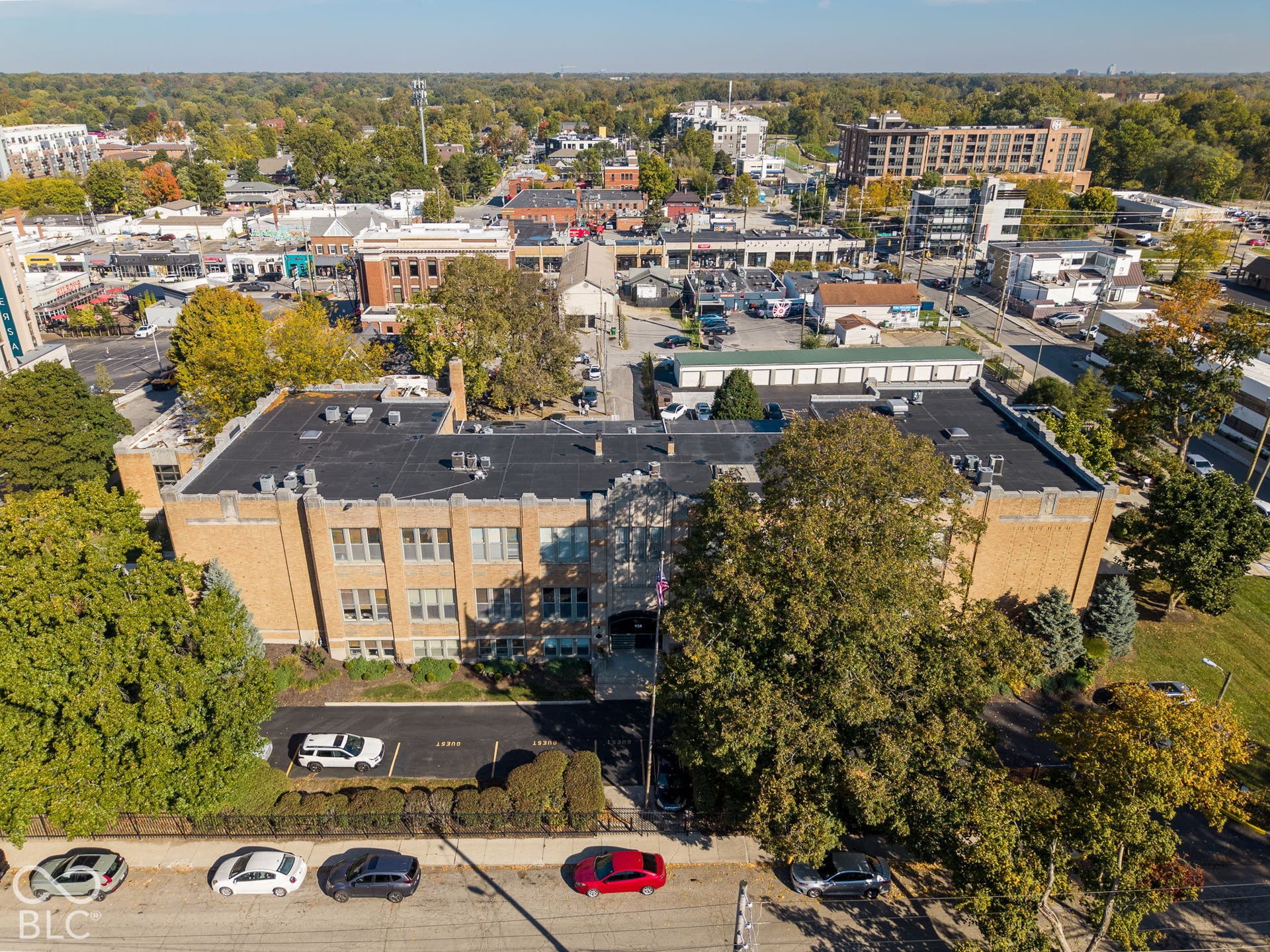 Masonry exterior building featuring a flat roof with parapet detailing, multi-pane windows, and a paved parking lot