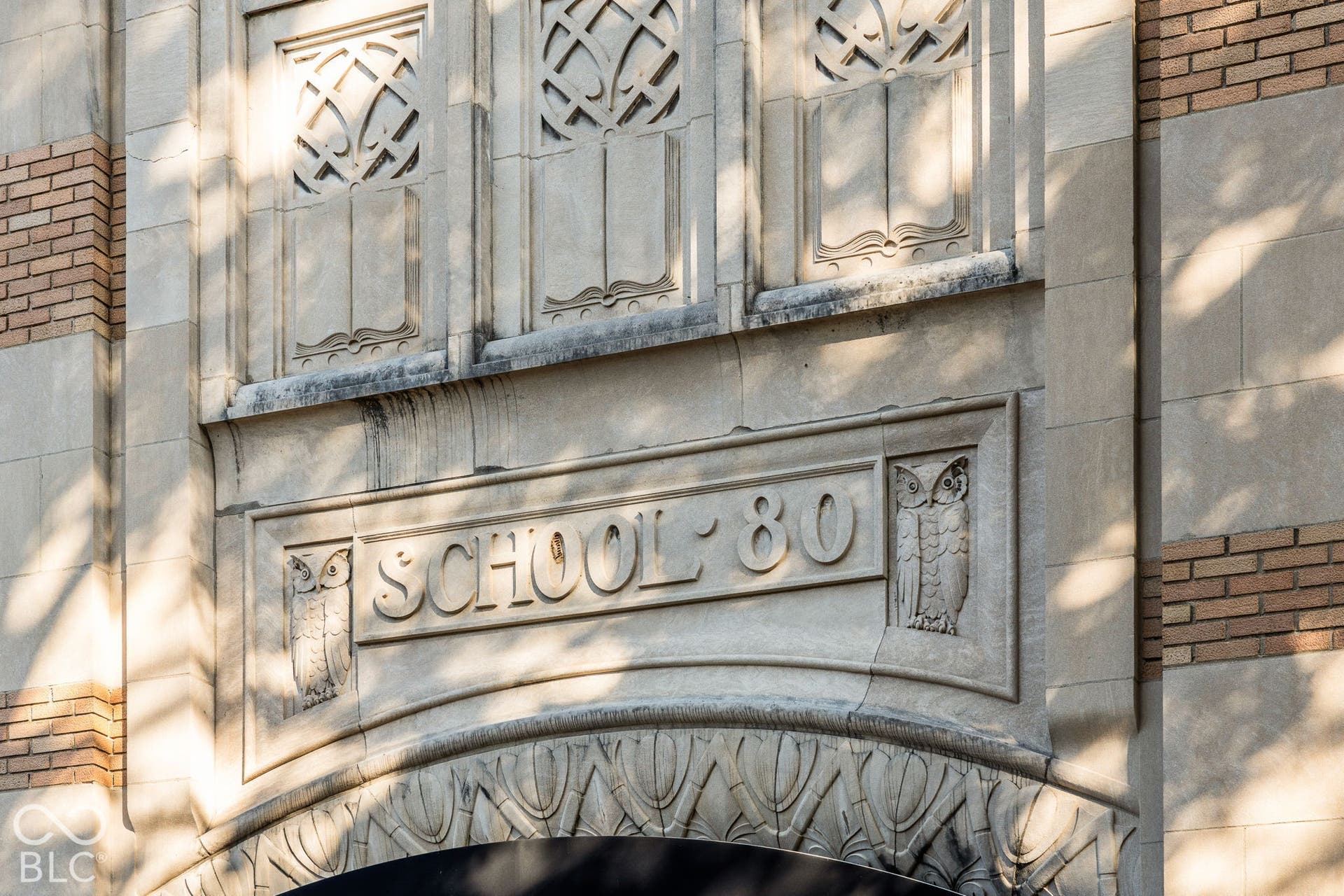 Exterior facade featuring intricate stone masonry, carved owl motifs, ornate arch detailing, and contrasting brick accents