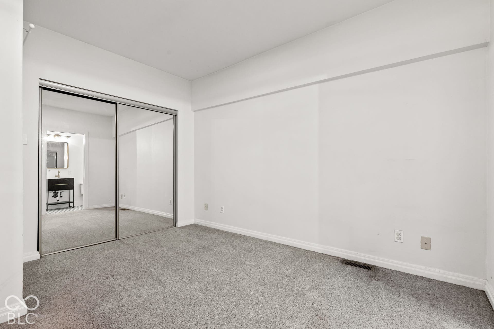 Room featuring neutral carpeting and floor-to-ceiling mirrored sliding closet doors