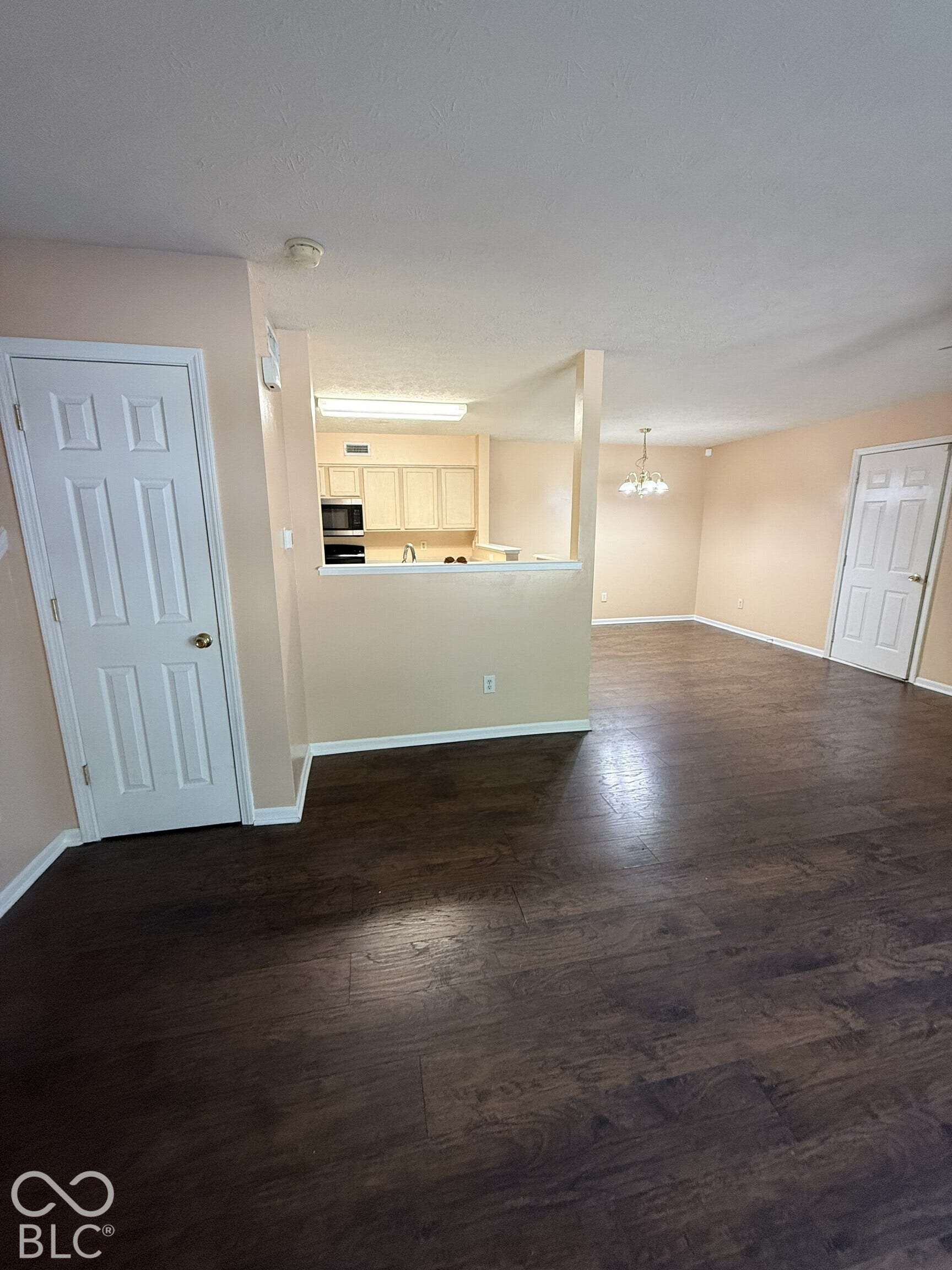 Open-concept interior featuring wood-finish flooring, a kitchen passthrough, built-in cabinetry, and multi-panel doors