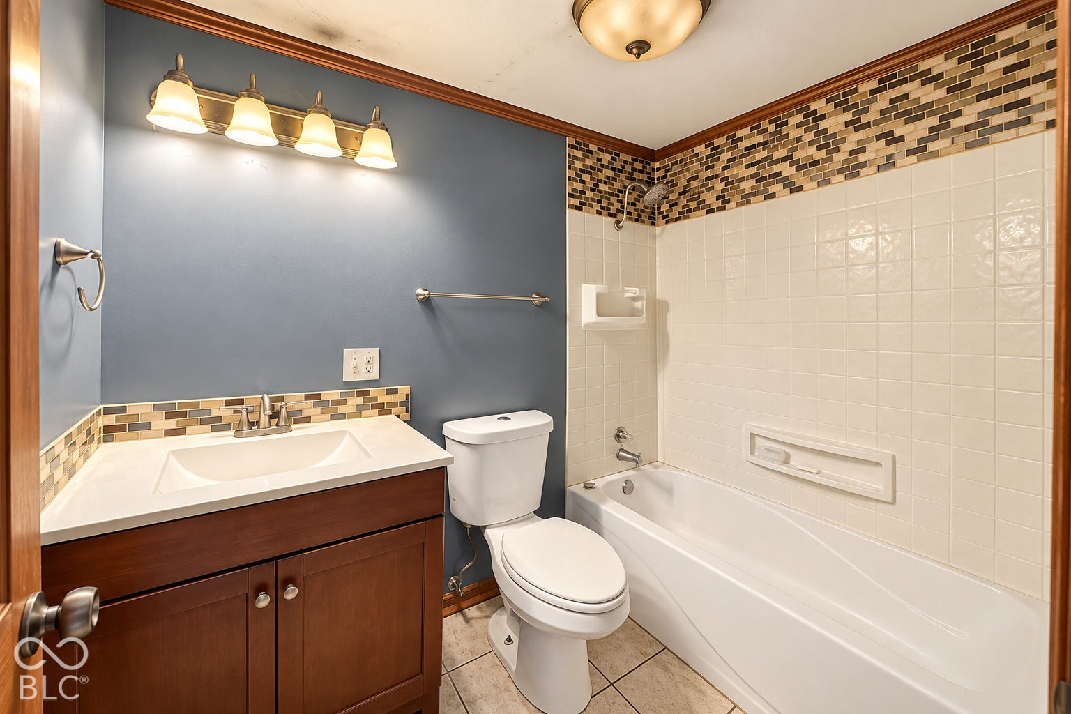 1802 Heather Court, Indianapolis, IN 46229 Virtually Altered - Bathroom featuring a dark wood-finish vanity with a solid surface countertop, glass and stone mosaic tile backsplash, full-size soaking tub with integrated shower surround, and ceramic tile flooring