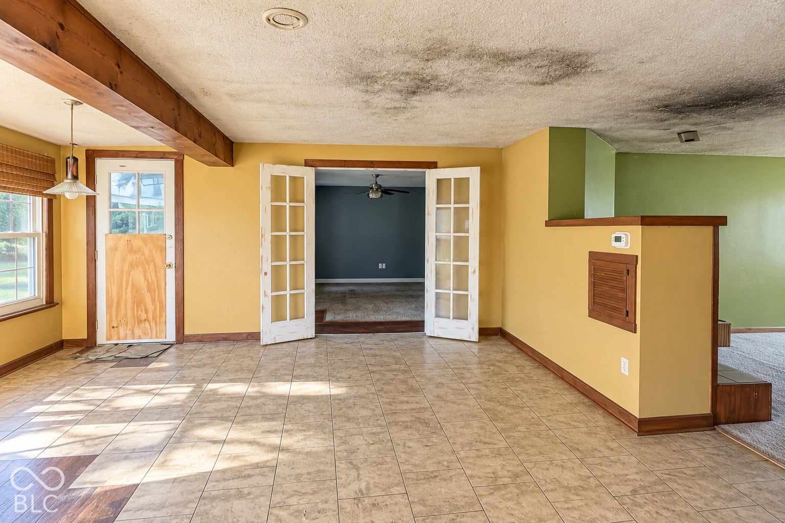 1802 Heather Court, Indianapolis, IN 46229 Virtually Altered - Tiled flooring, exposed wood beam ceiling detail, and double French doors with multi-lite glass panels
