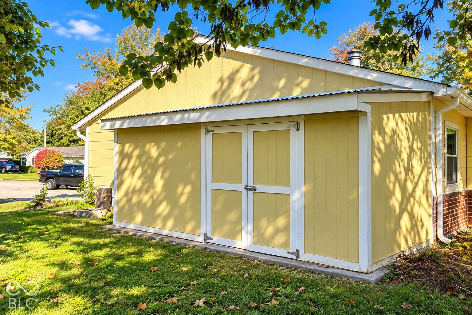 1802 Heather Court, Indianapolis, IN 46229 Virtually Altered - Detached storage building featuring vertical panel siding, double-door entry, corrugated metal roof trim, and a concrete foundation