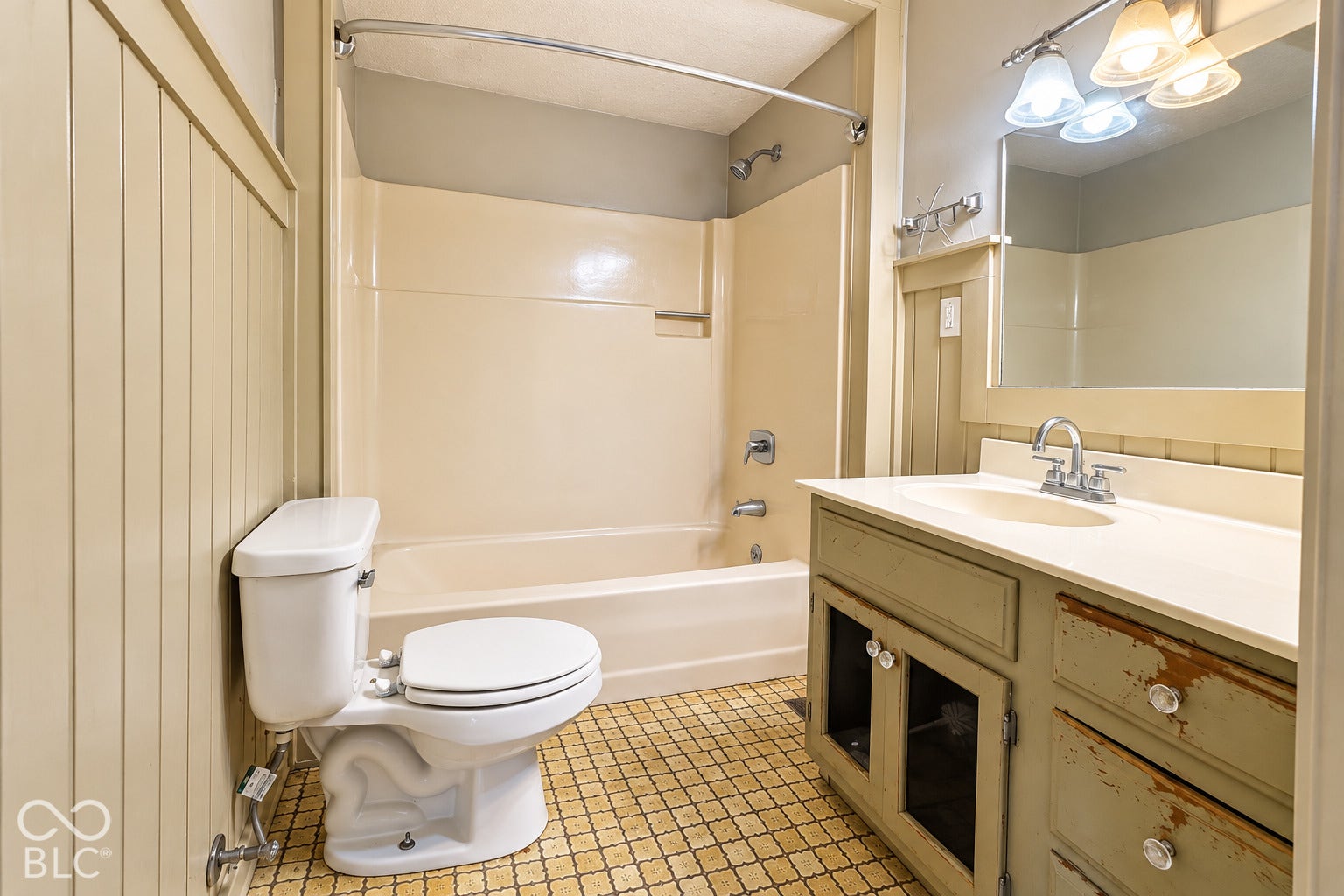 1802 Heather Court, Indianapolis, IN 46229 Virtually Altered - Bathroom featuring a vanity with integrated sink and cabinetry, wall-mounted mirror with multi-light fixture, tub-shower combination with surround, and wainscot wall paneling