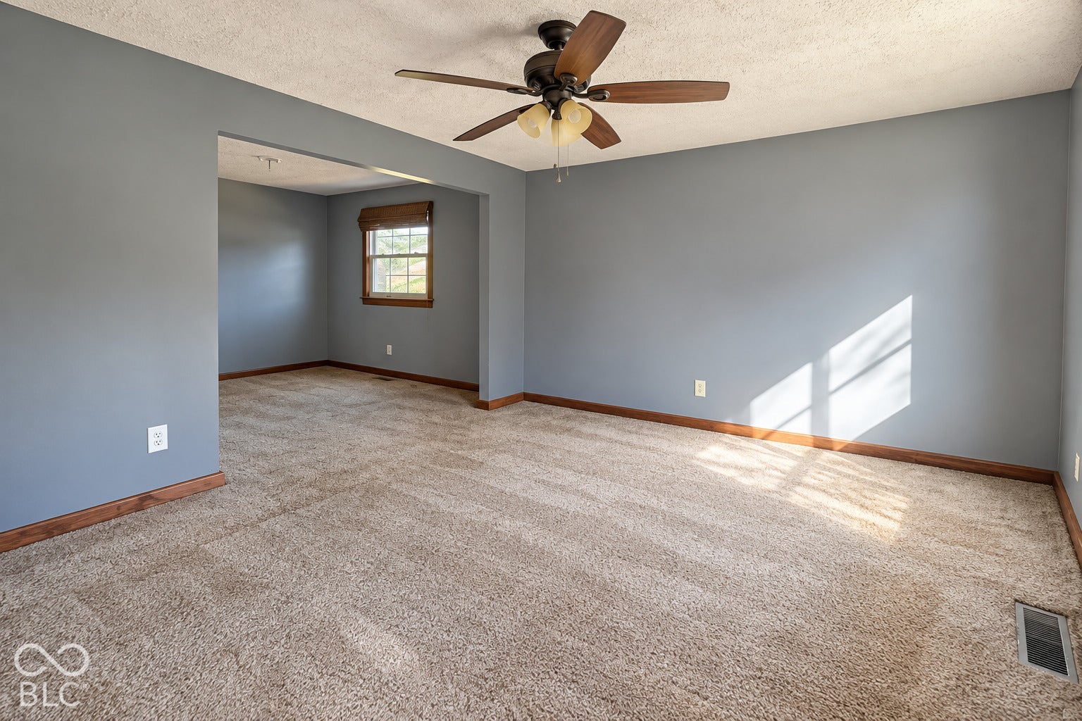 1802 Heather Court, Indianapolis, IN 46229 Virtually Altered - Neutral-toned interior featuring wall-to-wall carpeting, wood trim finishes, and a central ceiling fan with multi-light fixture