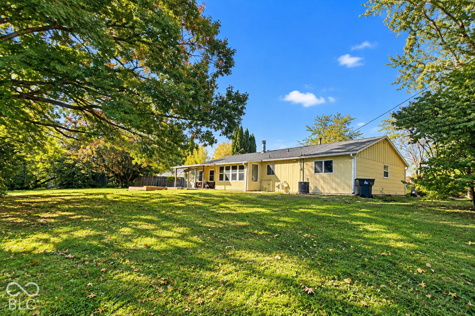 1802 Heather Court, Indianapolis, IN 46229 Virtually Altered - Exterior rear elevation featuring vertical siding, a sprawling lawn, and mature trees