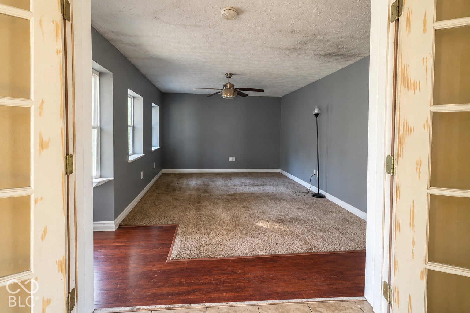 1802 Heather Court, Indianapolis, IN 46229 Virtually Altered - Interior space featuring French doors, wood-finish flooring, carpeting, wall-mounted ceiling fan, and multi-pane windows