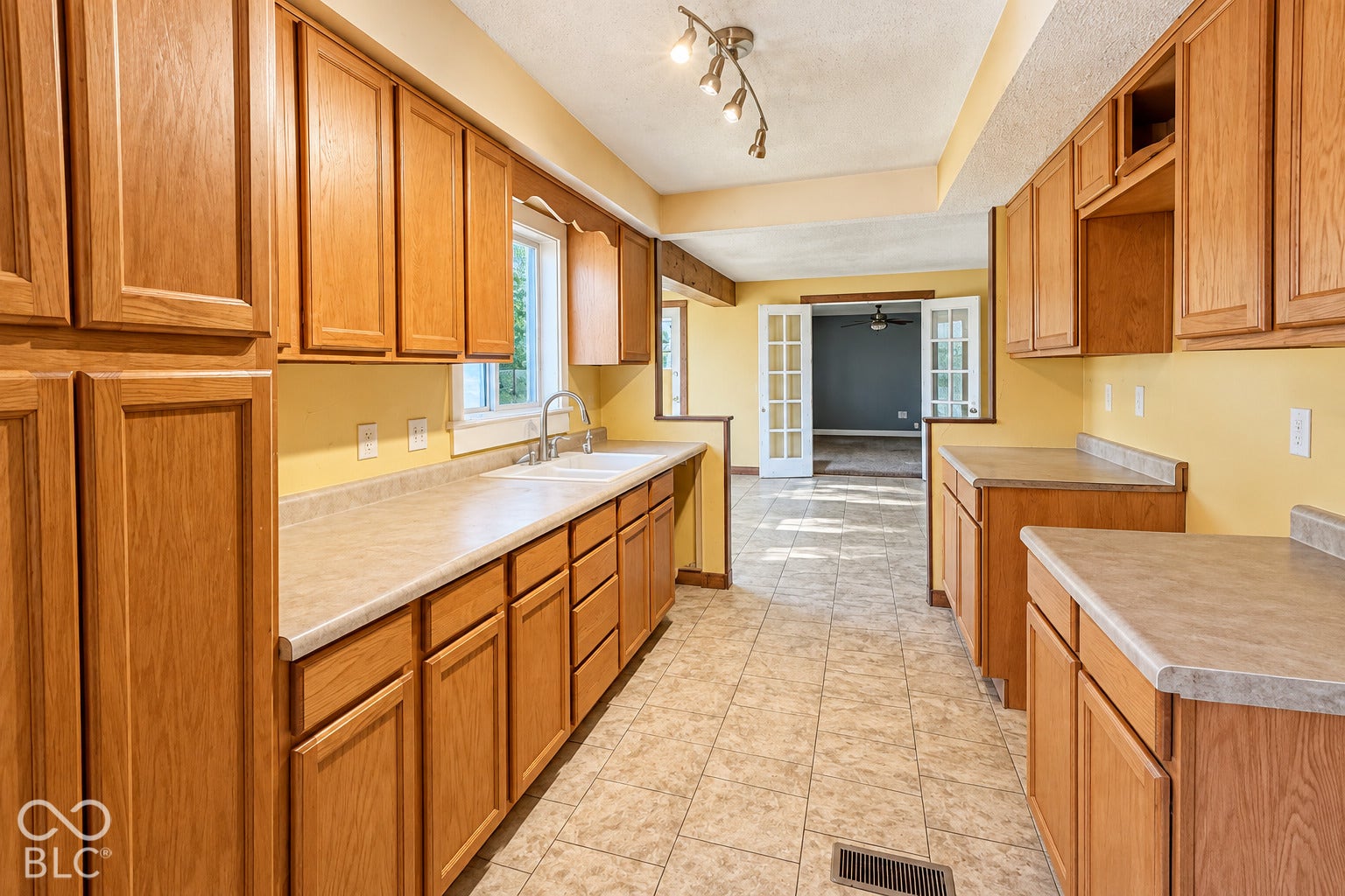 1802 Heather Court, Indianapolis, IN 46229 Virtually Altered - Kitchen featuring natural wood cabinetry, laminate countertops, a double-basin sink, tile flooring, and track lighting