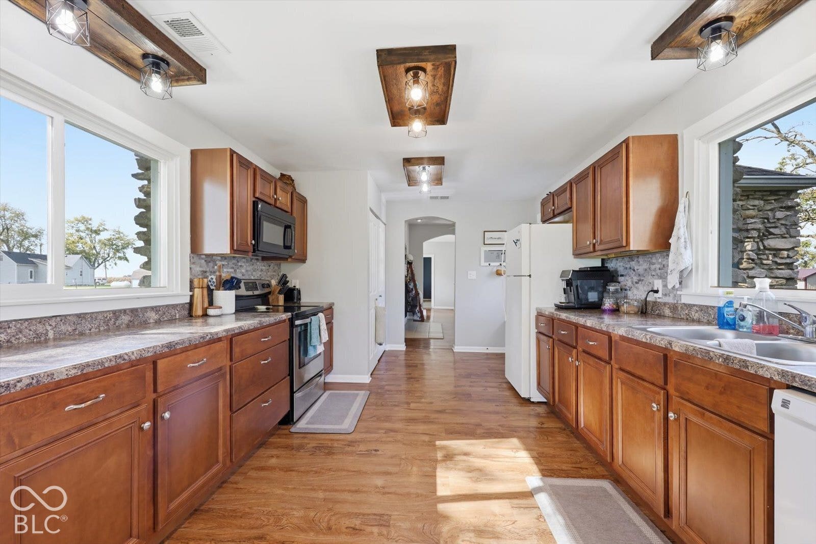 Kitchen featuring wood-finish cabinetry, wood-finish flooring, custom rustic-style overhead lighting fixtures, and dual picture windows