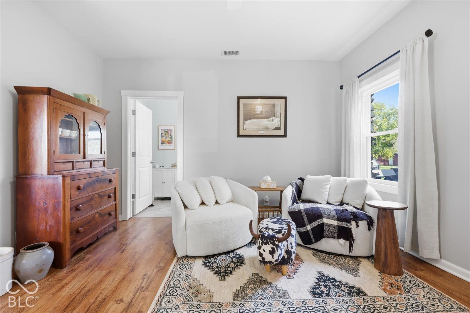 Interior space featuring wood-finish flooring, a double-hung window with white casing, and a six-panel door