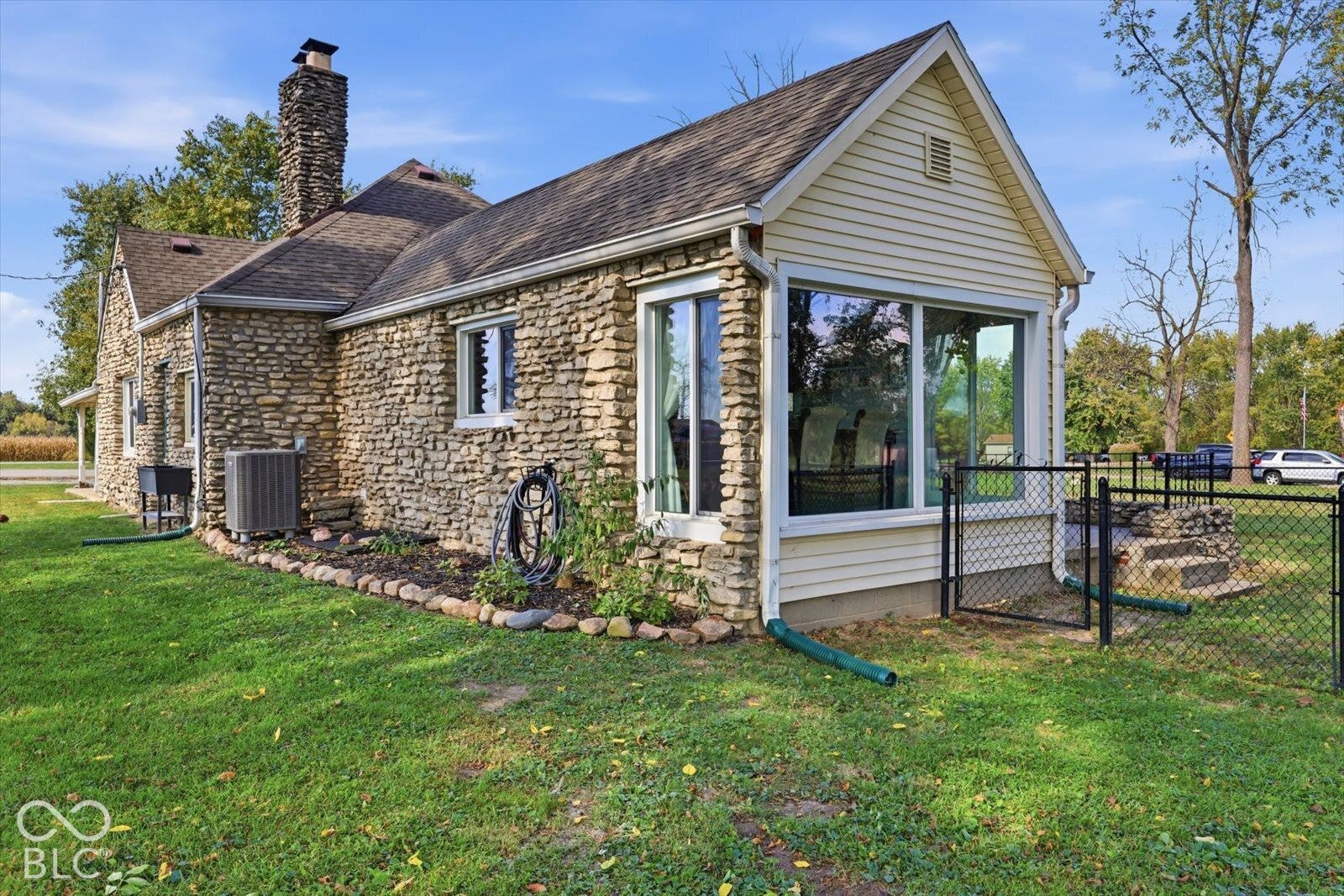 Stone exterior featuring a prominent chimney, horizontal siding, large picture wind