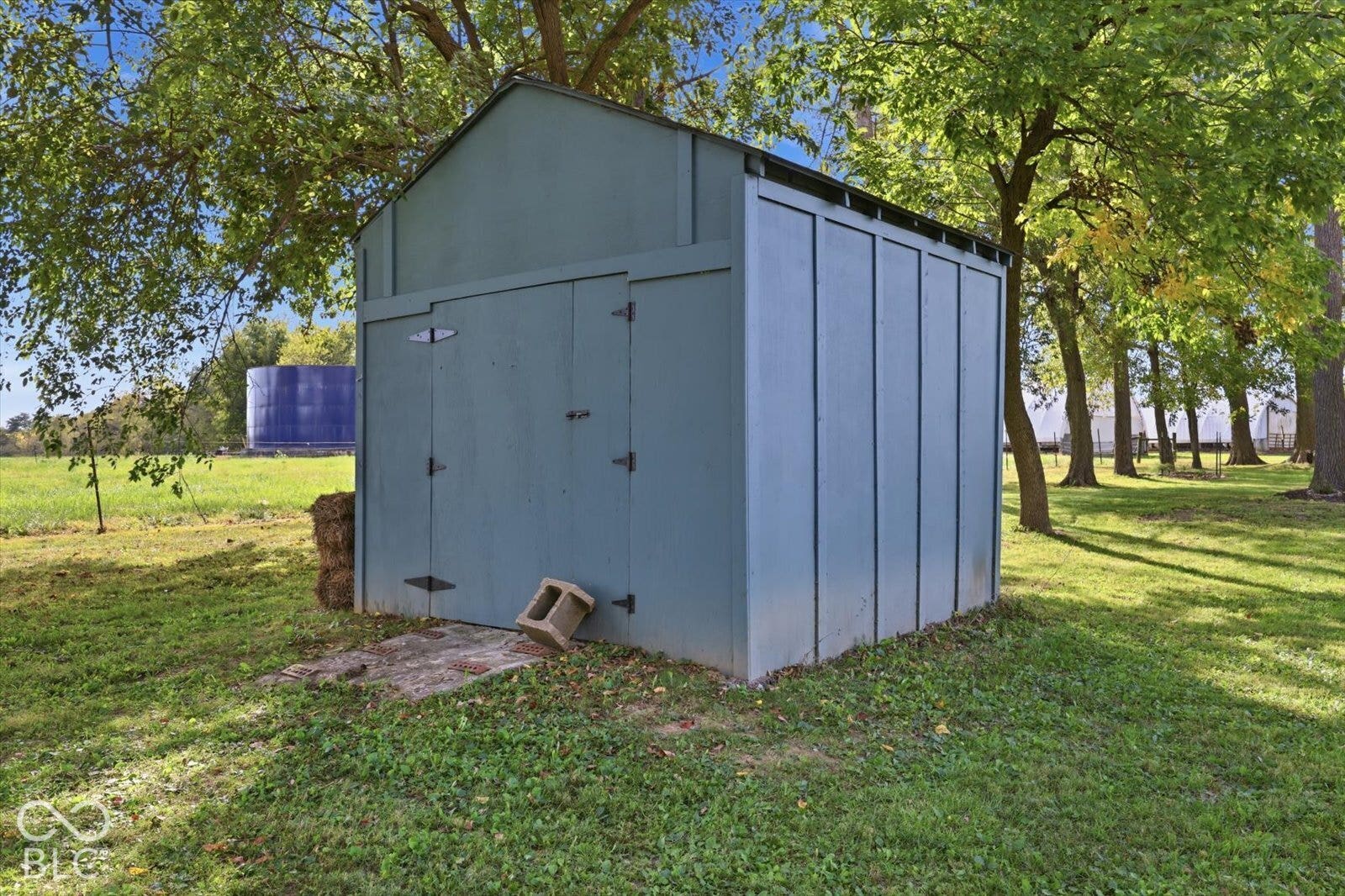 Detached gable-roof storage structure featuring vertical siding, dual swinging doors, and metal hardware