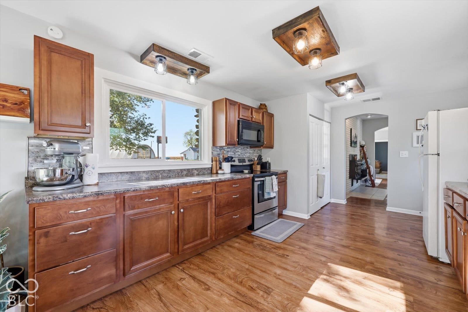 Kitchen featuring stained-wood cabinetry, stone-finish countertops, wood-finish flooring, and custom wood-frame ceiling lighting fixtures