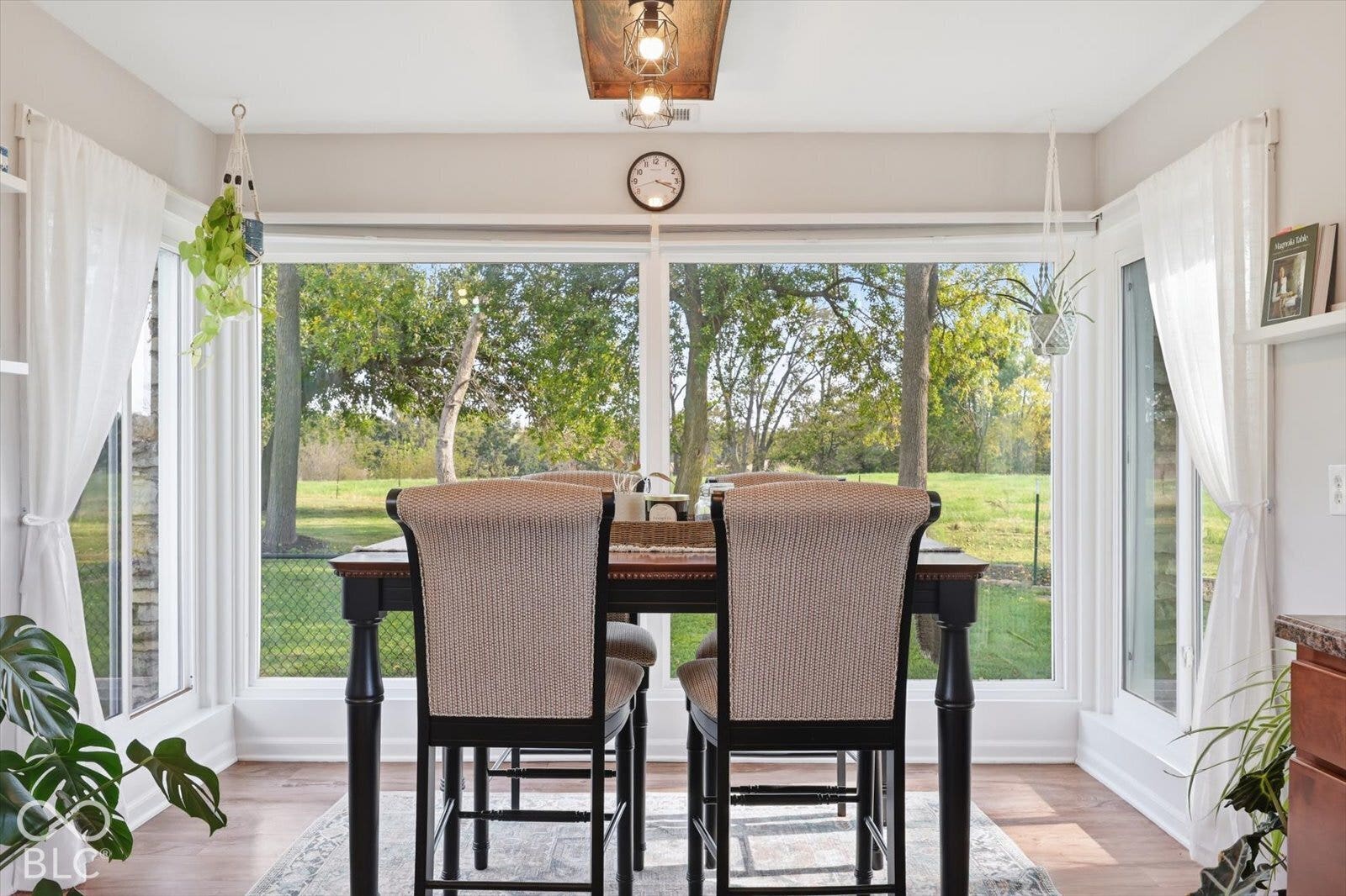 Expansive multi-pane window configuration featuring wood-finish flooring and a rectangular hanging light fixture with a metallic finish