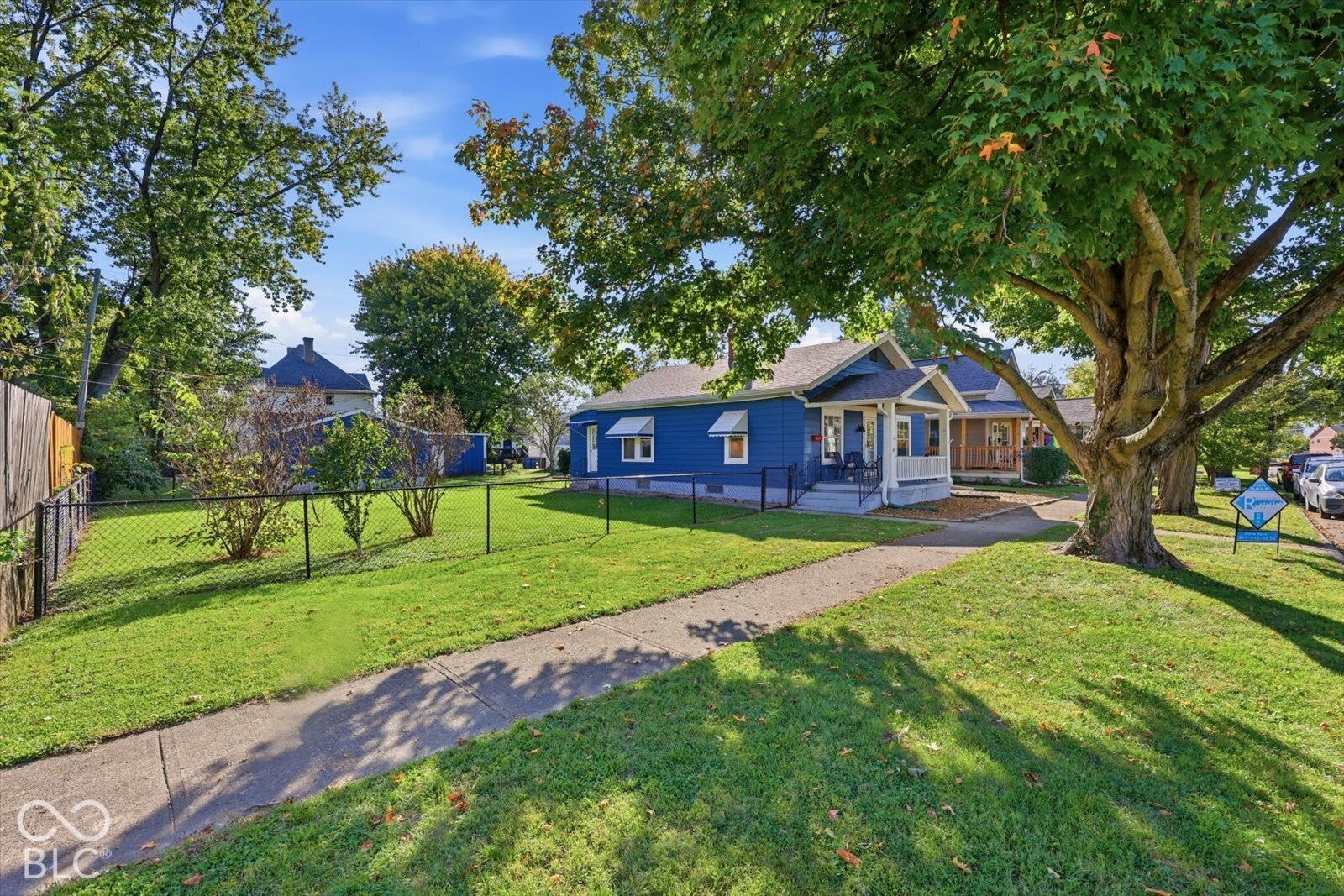 Blue-sided exterior featuring a front porch, chain-link fenced yard, and detached garage