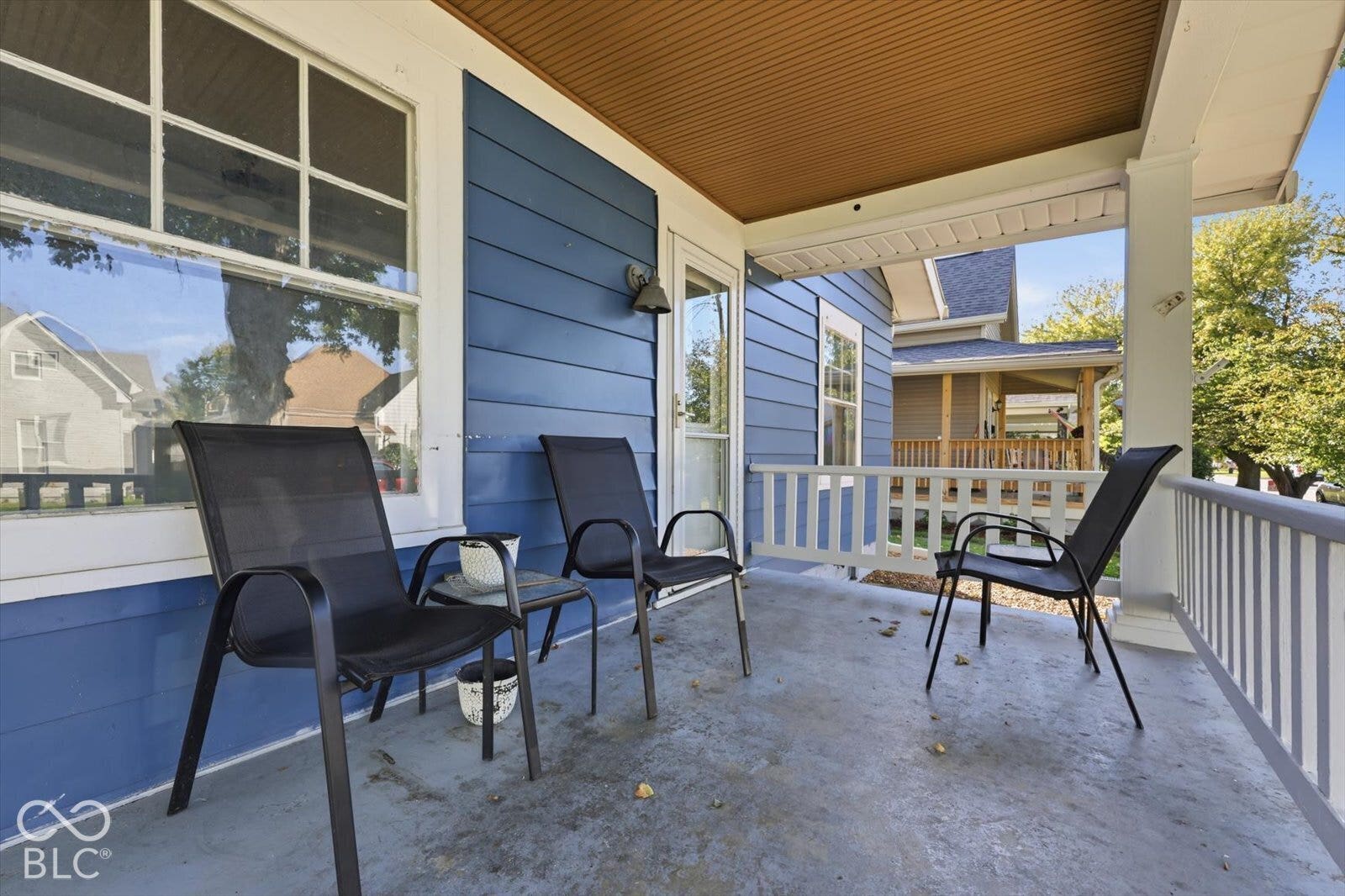Covered front porch featuring blue horizontal lap siding, a painted concrete floor, white wood railing, and a beadboard ceiling