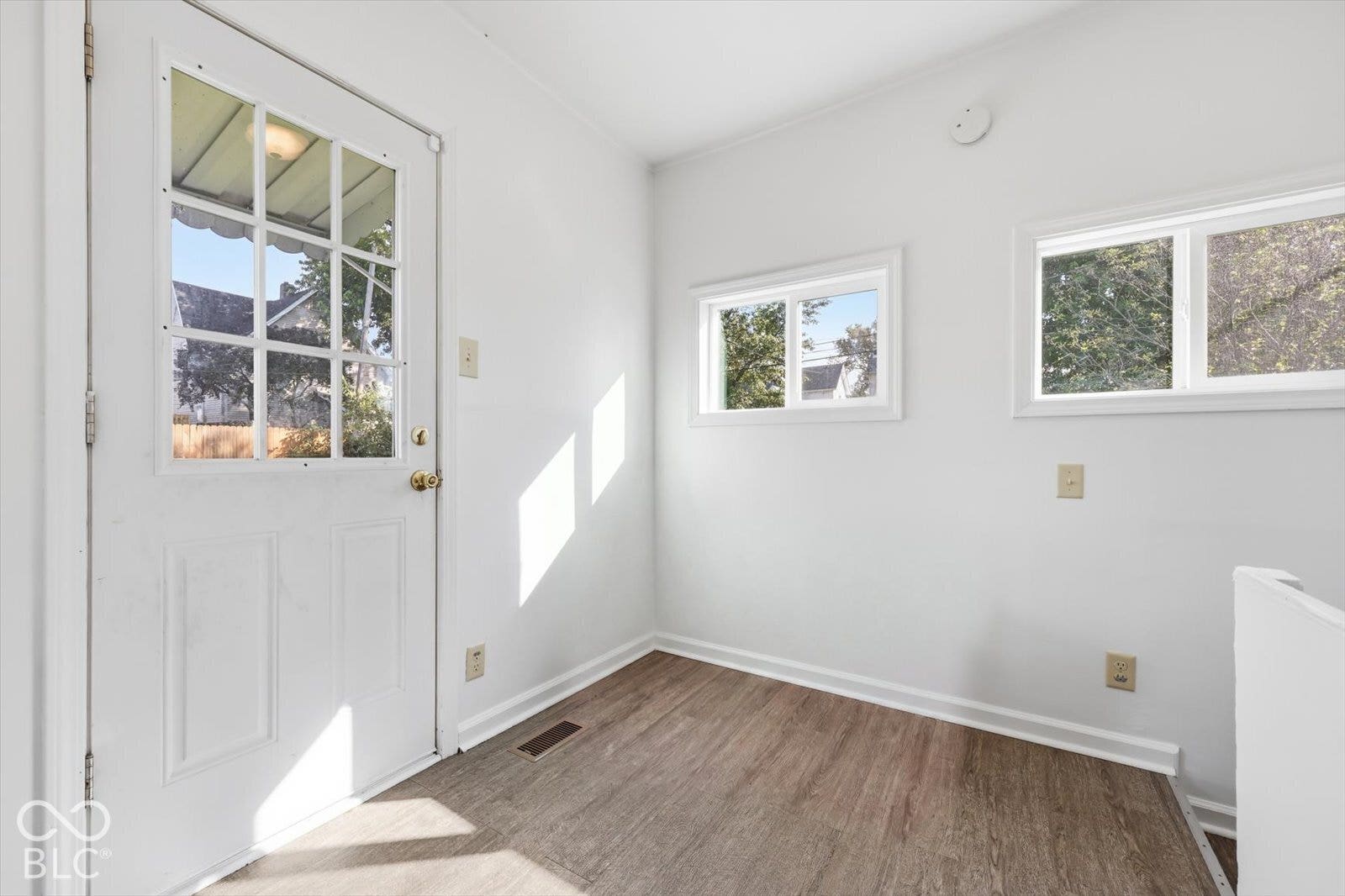 Wood-finish flooring, two sliding windows, and a glass-paneled exterior entry door