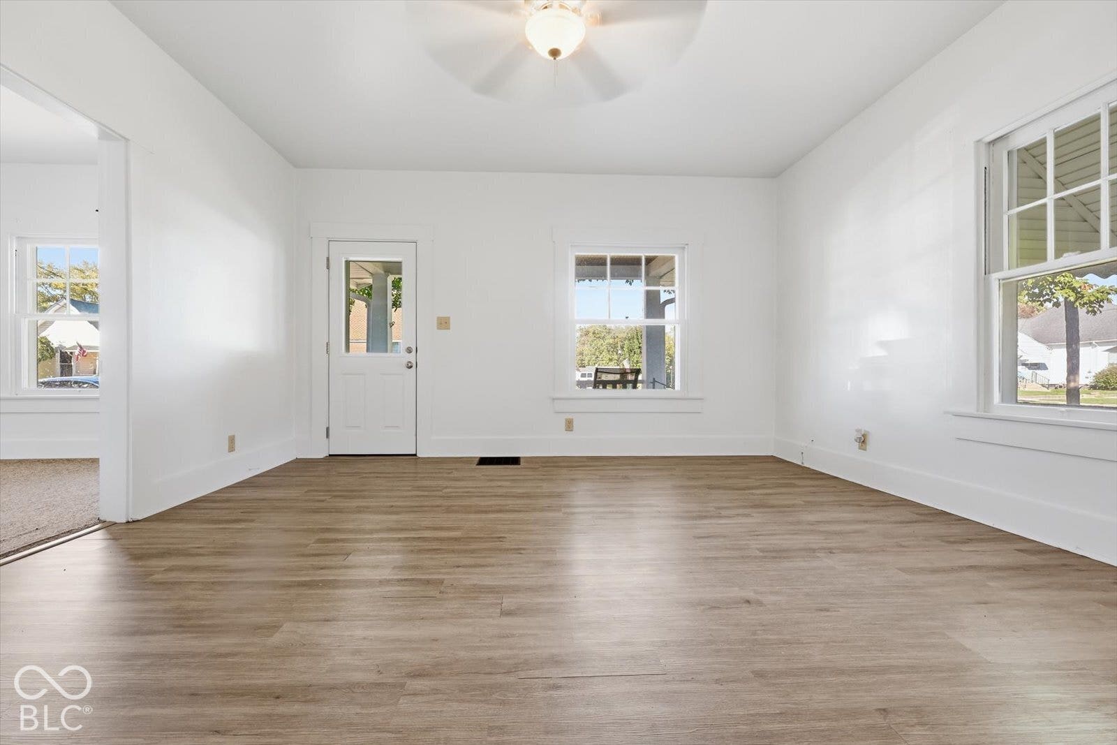 Interior space featuring wood-finish flooring, multi-pane windows, a central ceiling-mounted light fixture, and a white exterior-access door with a glass panel