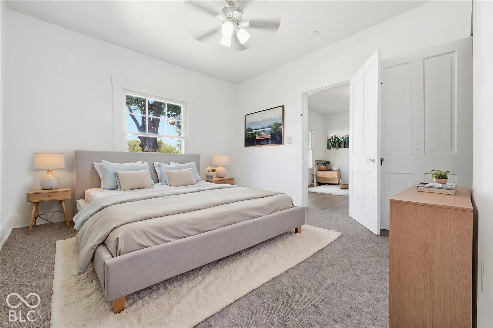 Virtually Altered - Neutral interior room featuring neutral carpeting, a multi-pane window, and an attached ceiling fan with integrated lighting