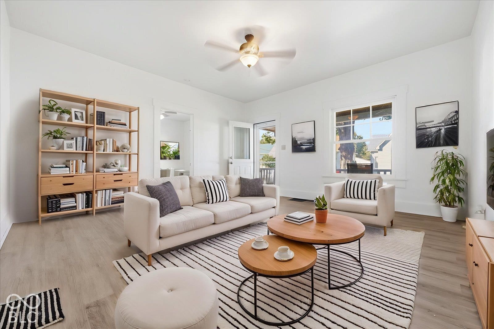 Living area featuring wood-finish flooring, high ceilings, a ceiling fan with integrated lighting, and multi-pane windows with detailed trim