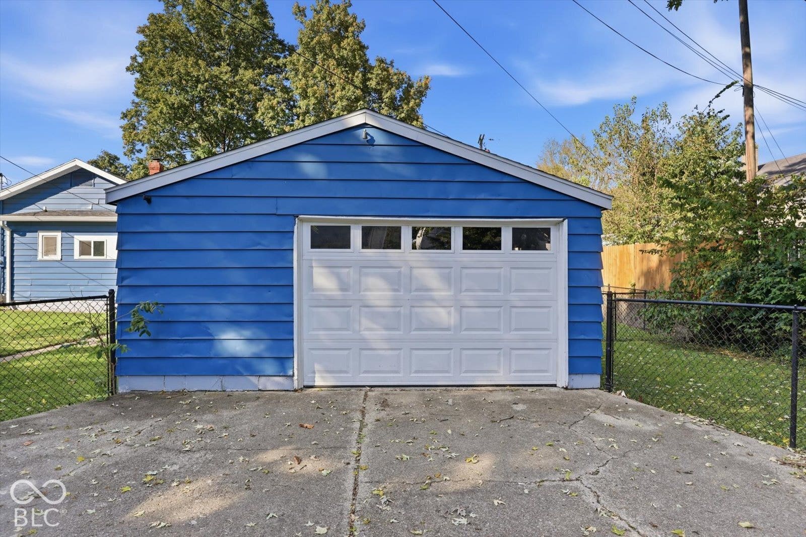 Detached garage featuring blue lap siding, a sectional garage door with window inserts, and a concrete driveway apron