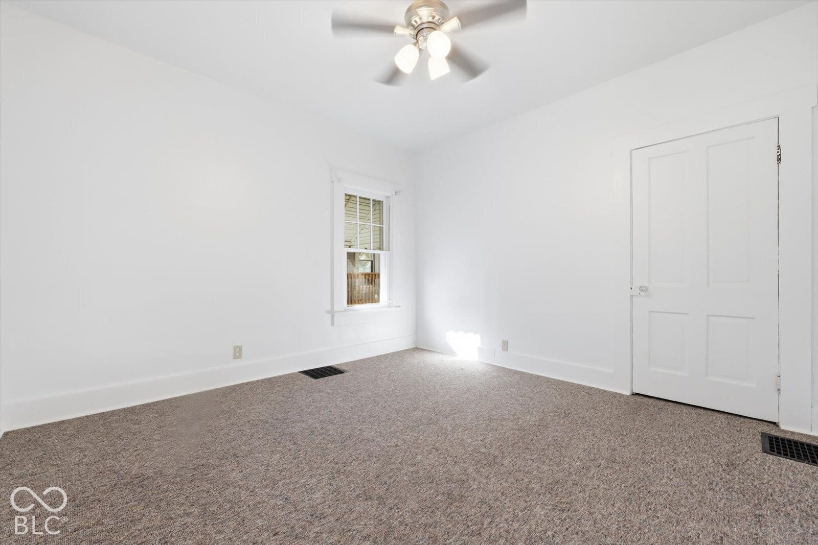 Interior space featuring wall-to-wall carpeting, a single-hung window with decorative molding, and a four-panel interior door