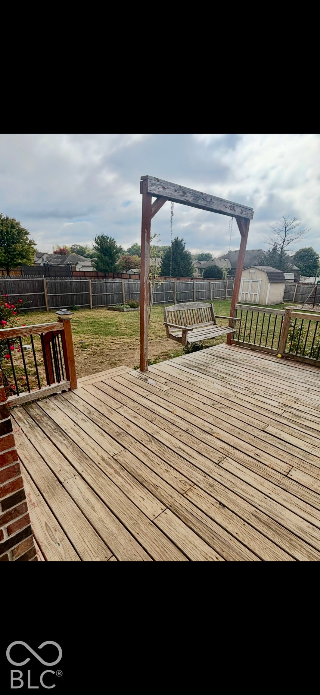 Wood deck featuring integrated railings with metal balusters, privacy fencing, and a detached storage structure