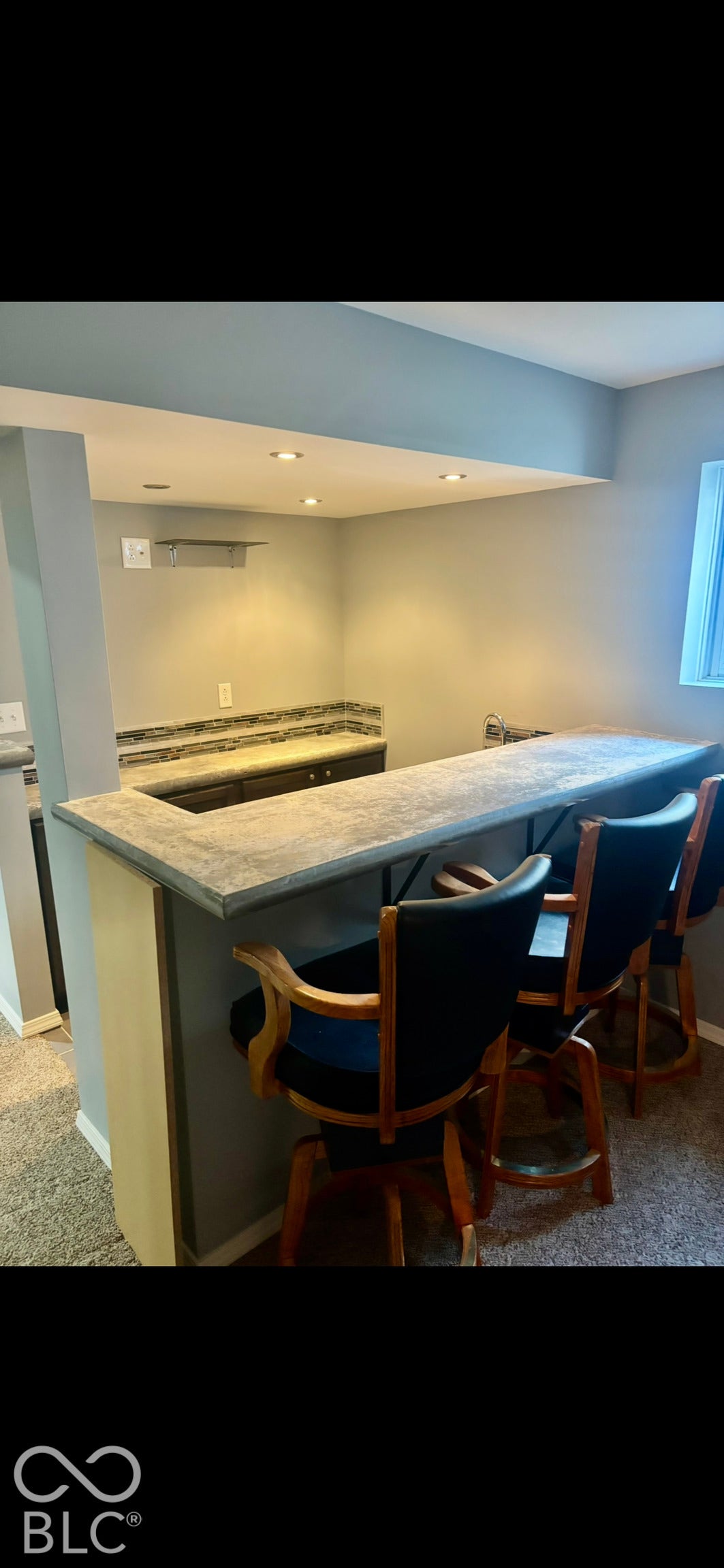 Wet bar featuring a stone-surface countertop, dark cabinetry, decorative stone backsplash, and recessed ceiling lighting