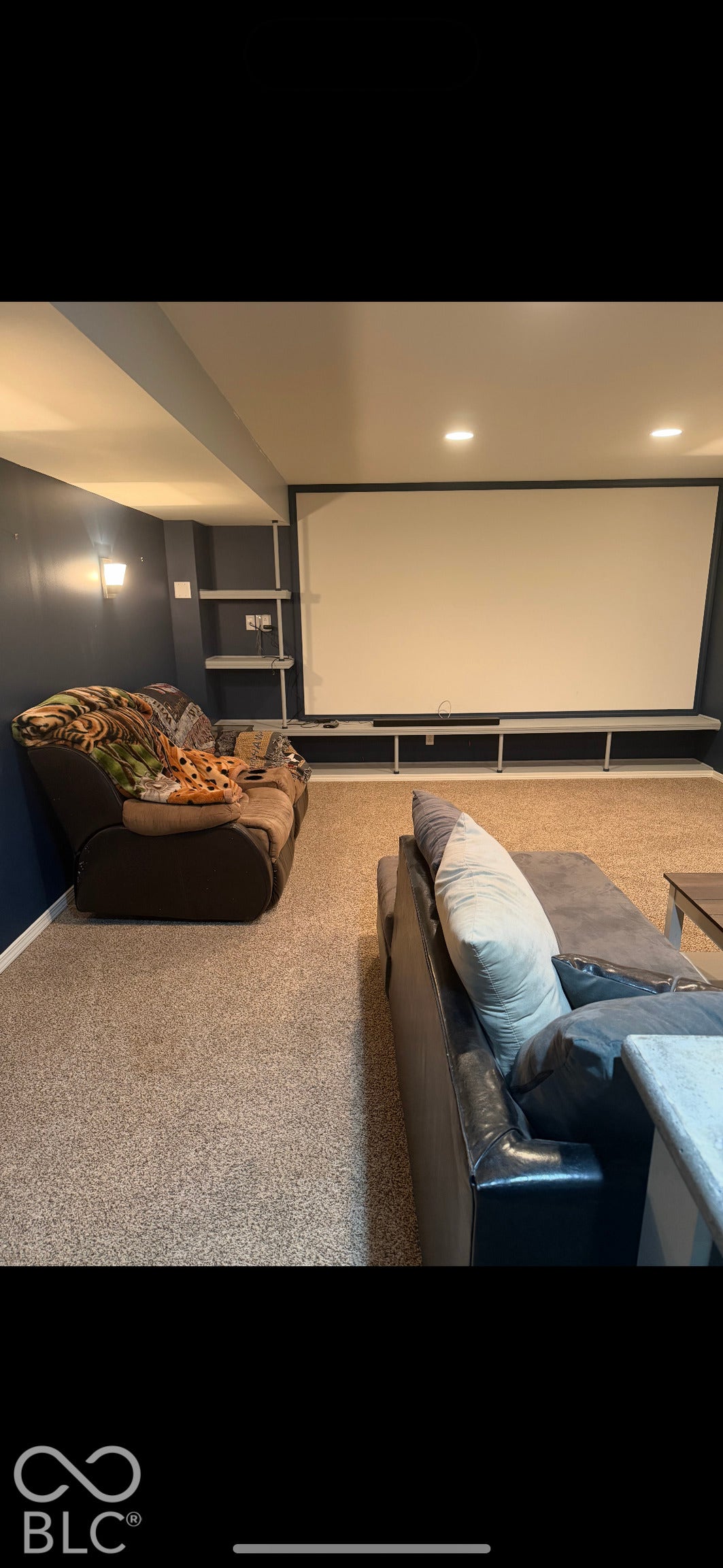 Built-in projection screen, wall-mounted display shelving, recessed lighting, and wall-mounted sconce