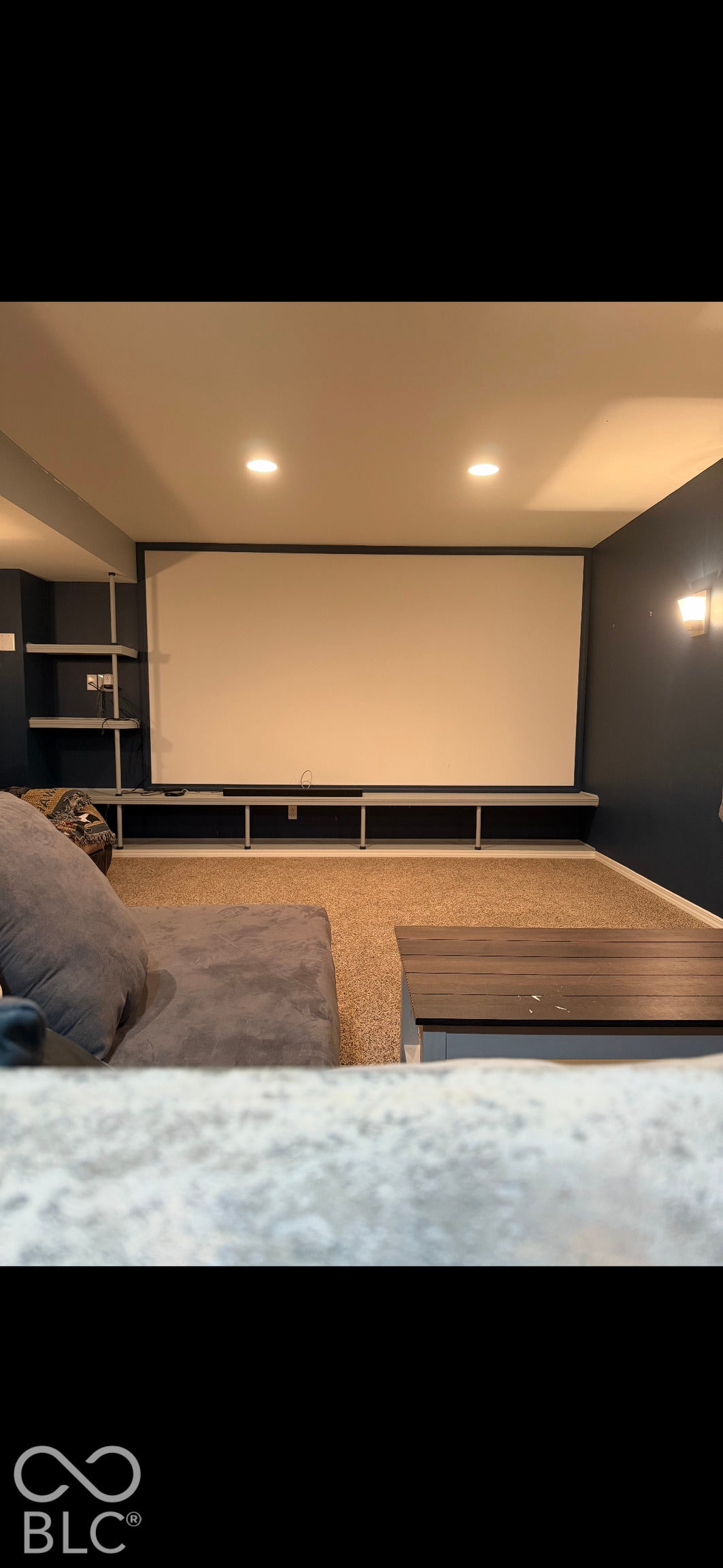 Recessed lighting, wall-mounted projector screen, built-in shelving, and carpeting