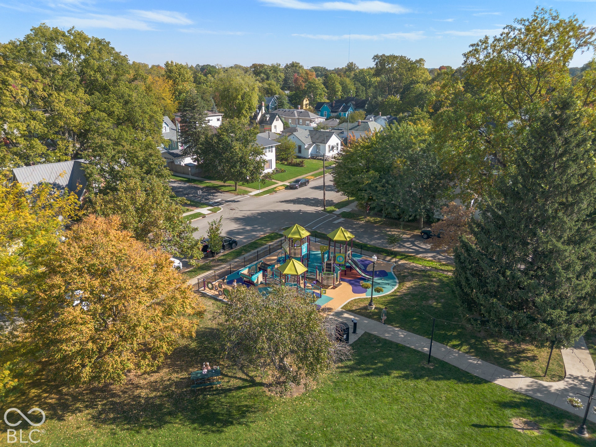 Public park featuring Public park featuring playground, walking paths, mature trees, and expansive green space.