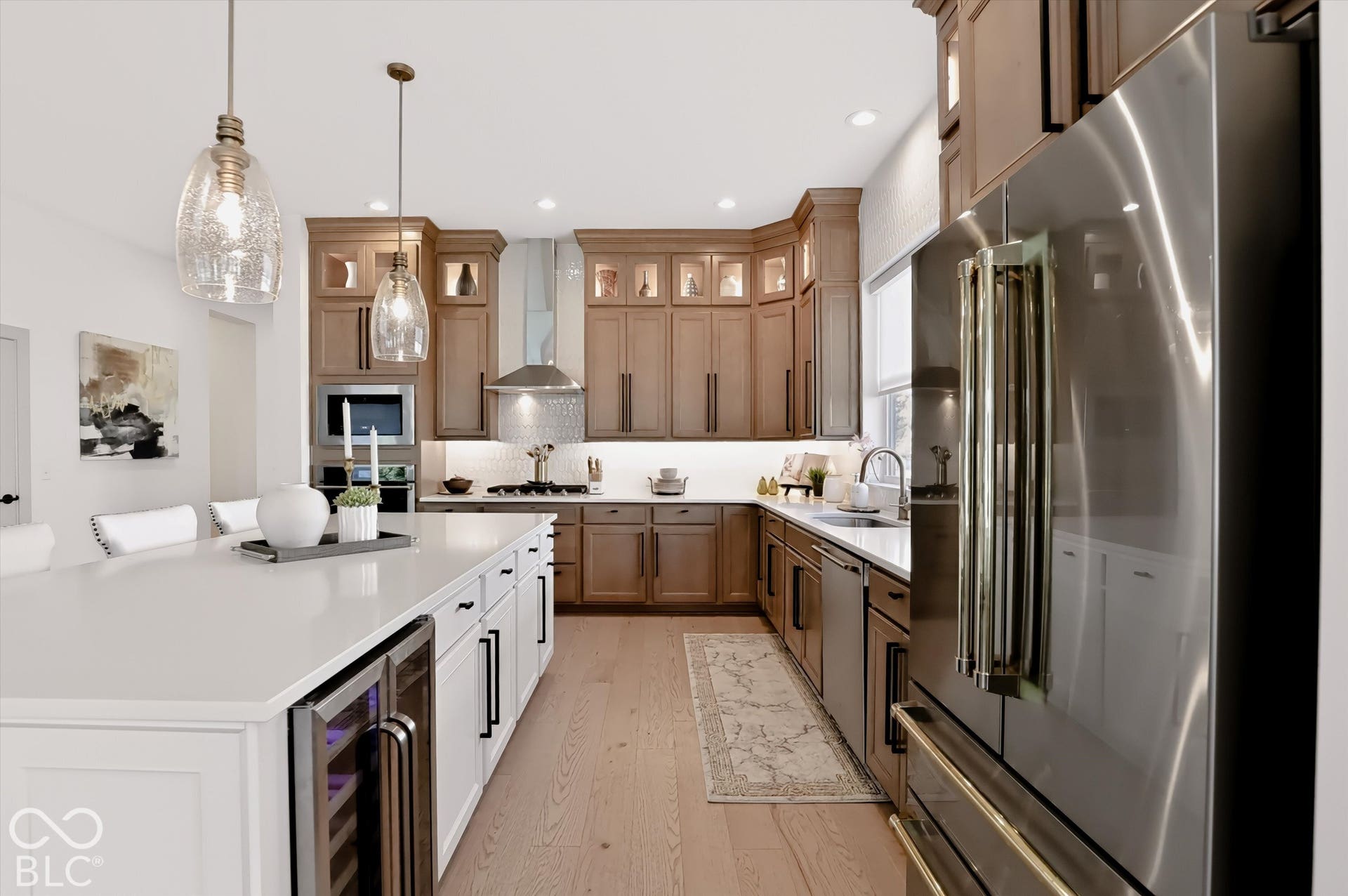Kitchen featuring shaker-style cabinetry, quartz countertops, a stainless steel refrigerator, wood-finish flooring, and pendant lighting