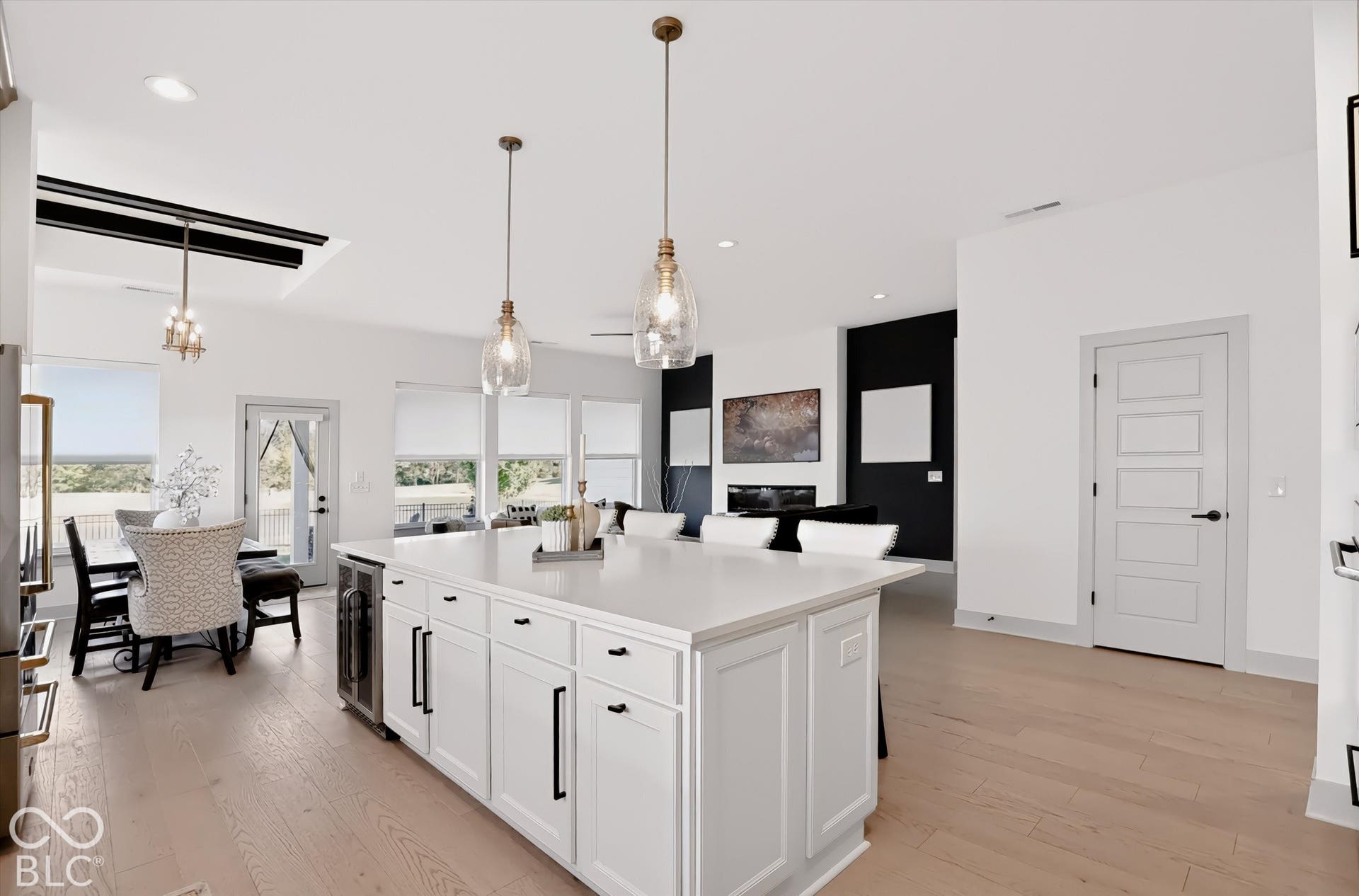 Kitchen featuring a large central island with quartz countertops, custom shaker-style cabinetry, wood-finish flooring, glass pendant lighting, and a built-in wine refrigerator